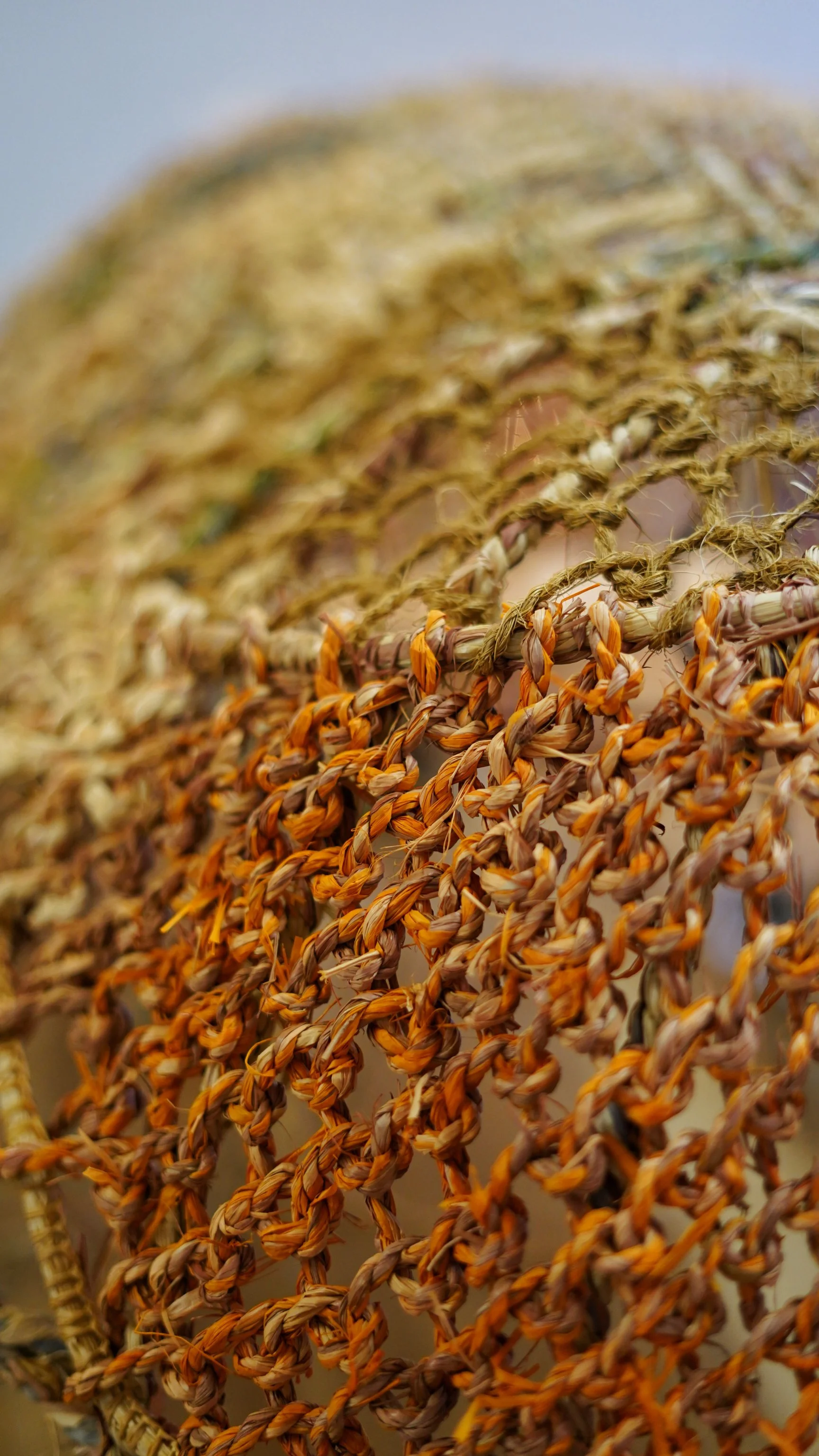 Close-up of woven straw or grass, with orange and beige fibers, forming a detailed pattern.