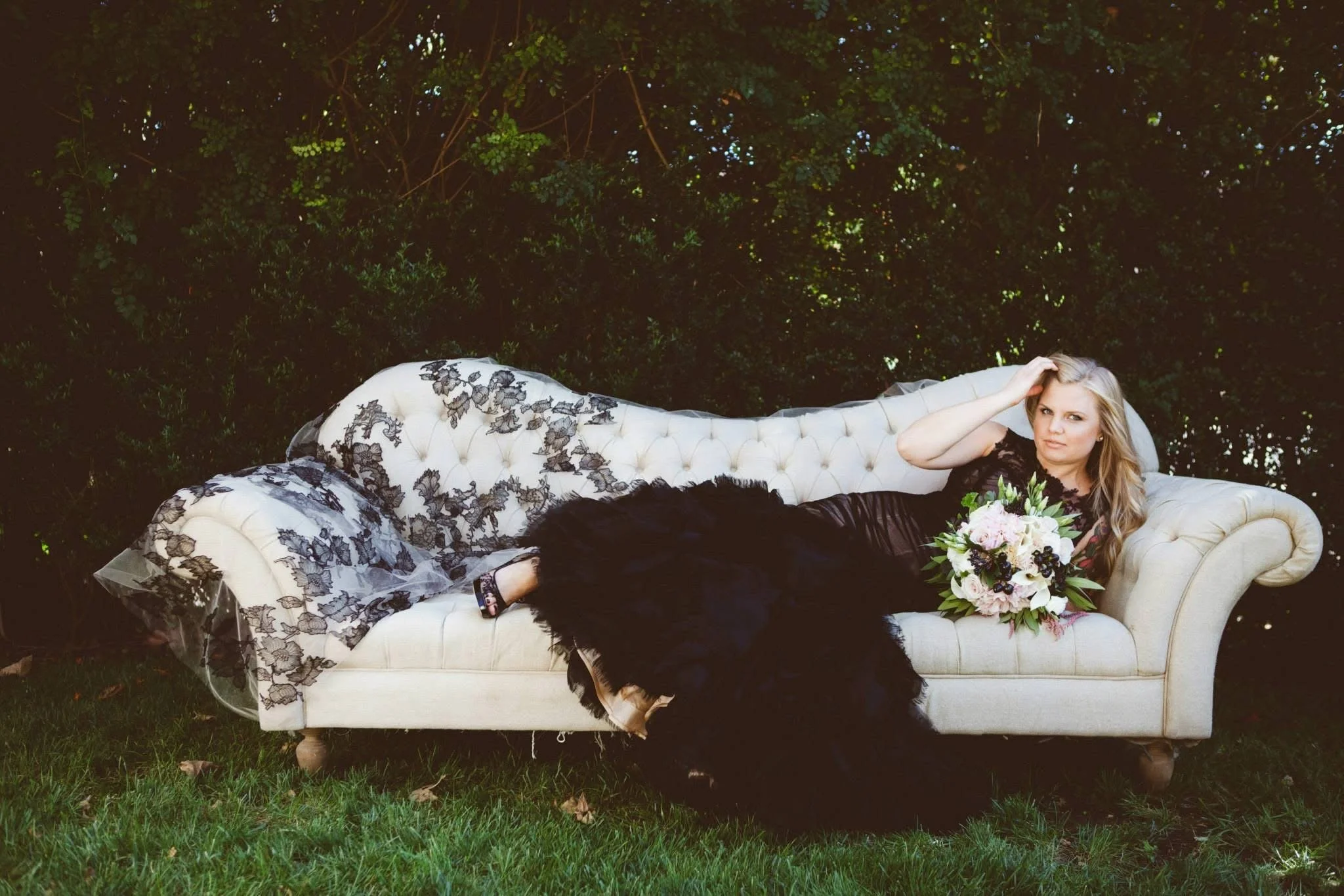 wedding florist reclining on a white sofa wearing her black non traditional wedding dress