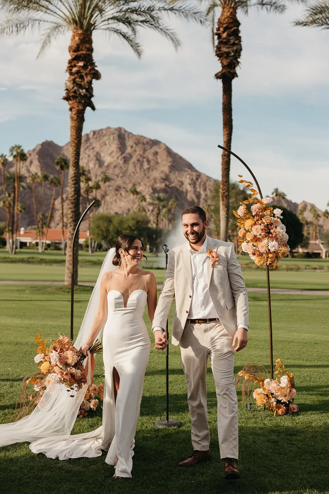  Bride and groom walking back down the aisle hand in hand, celebrating after their ceremony at La Quinta Resort. 