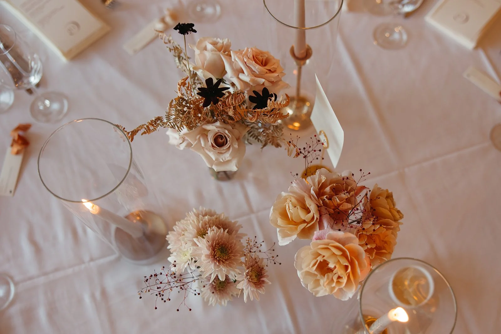  Overhead view of a wedding tablescape with blush roses, soft peach blooms, airy foliage, and candlelight at La Quinta Resort. 