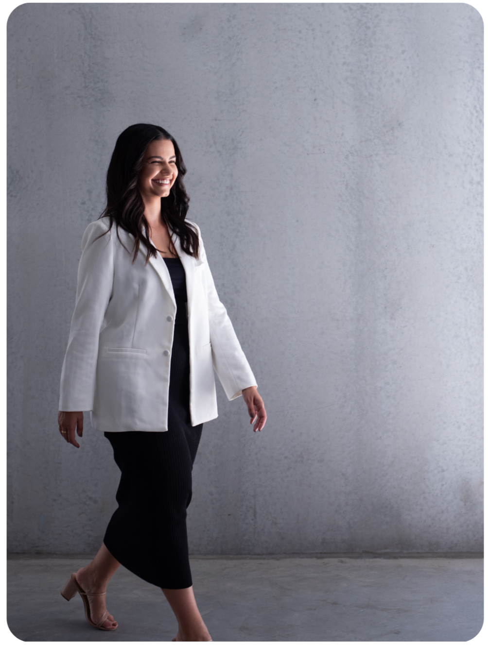 A woman with dark hair smiling and walking in a room.