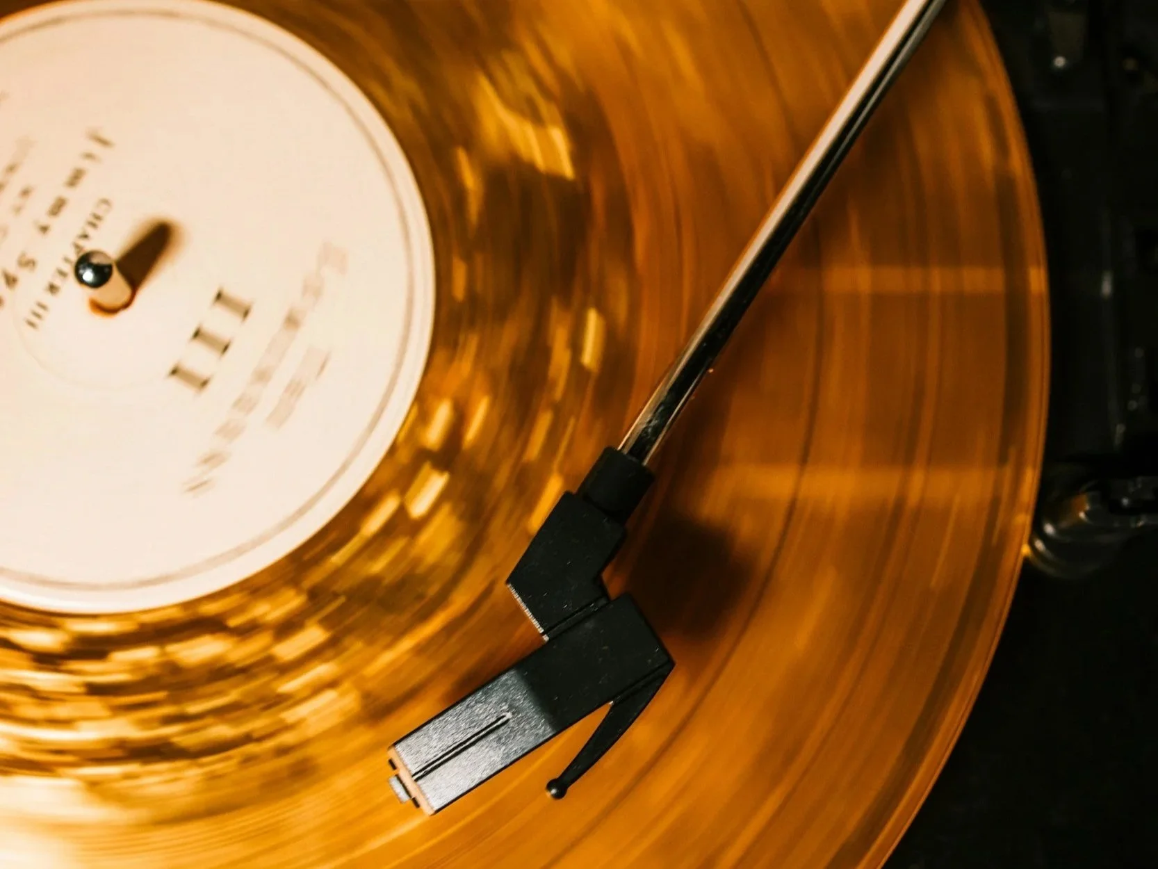 Close-up of a vintage turntable with a spinning brown record, a black tonearm, and a white label on the record.