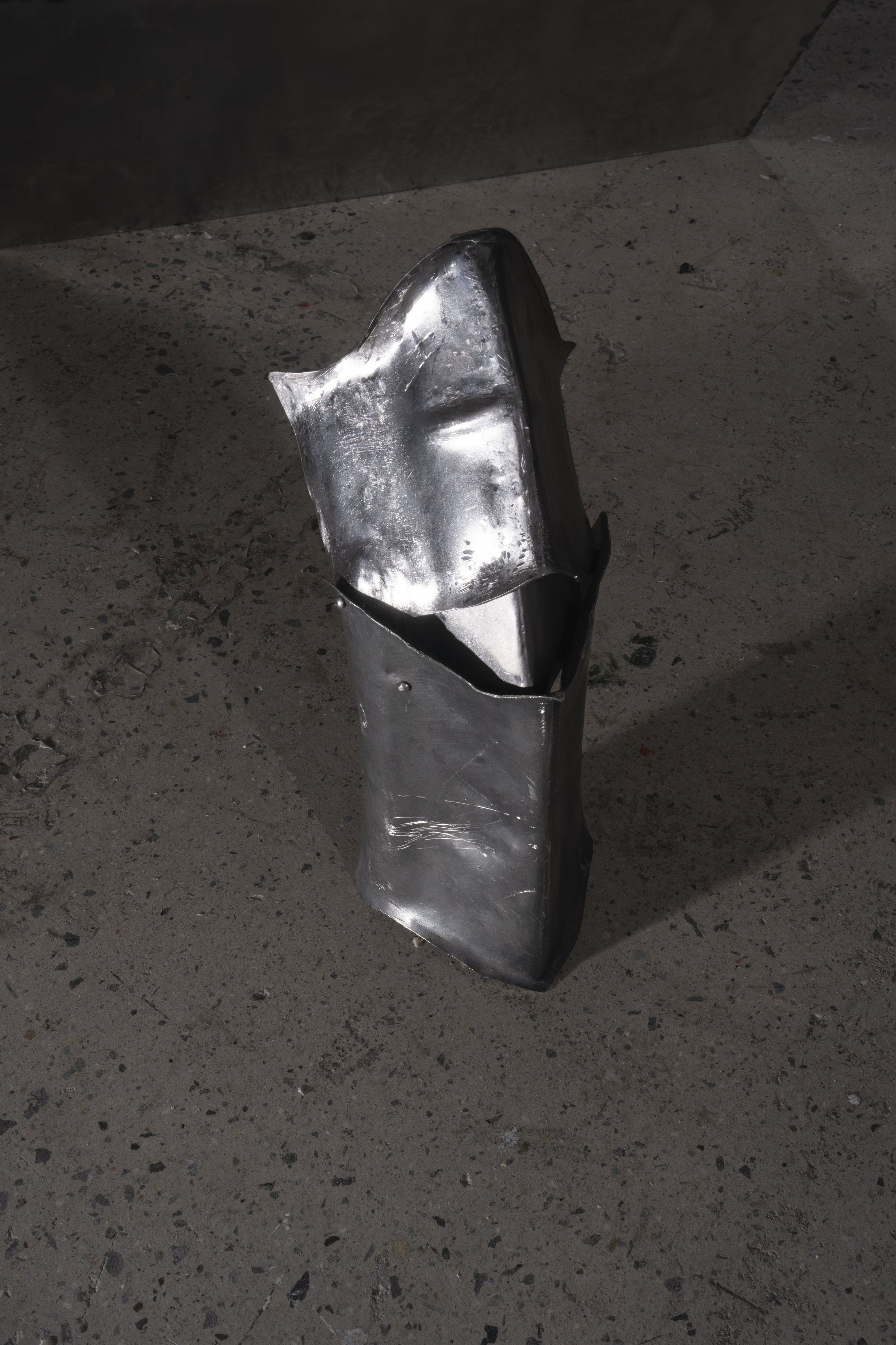 Jointed poleyn and greave forged with heat, weathered with patina, raised and shaped through hammering.