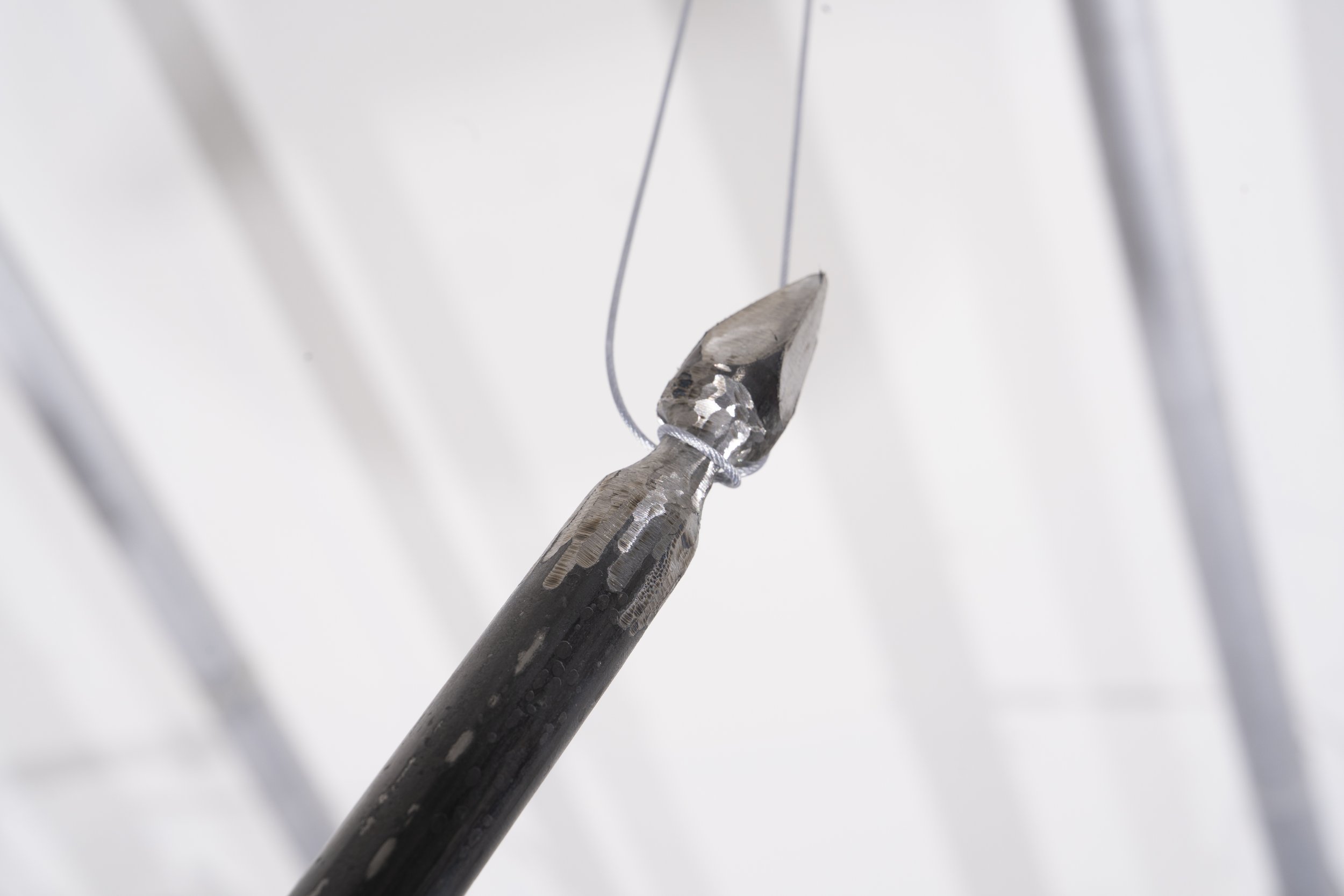 Spear made of solid steel articulated through plasma cutting, welding, grinding, polishing, and aged with patina.
