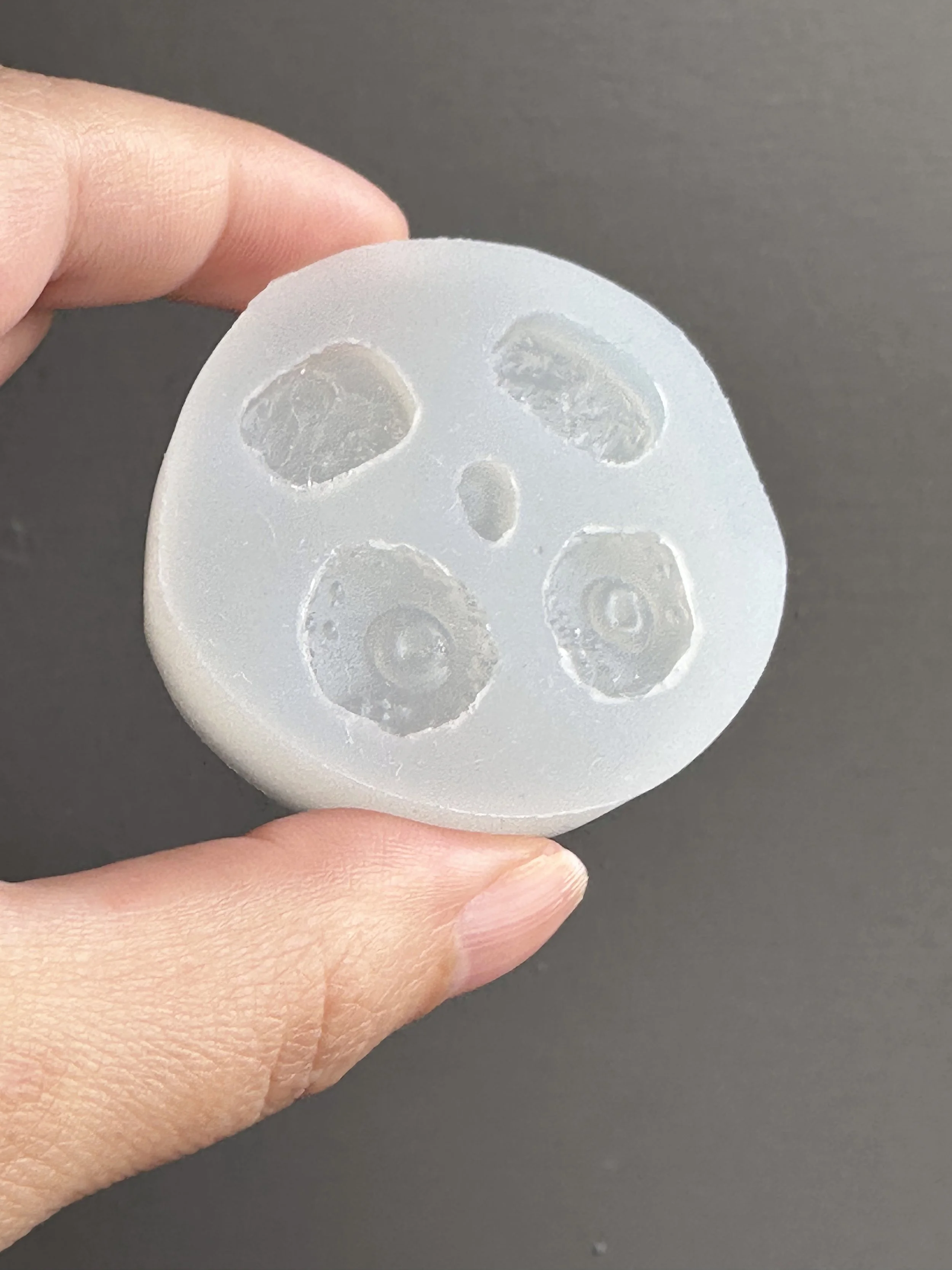 A hand holding a hash browns and fried eggs silicone mold, with a hard boiled egg half element in the center.