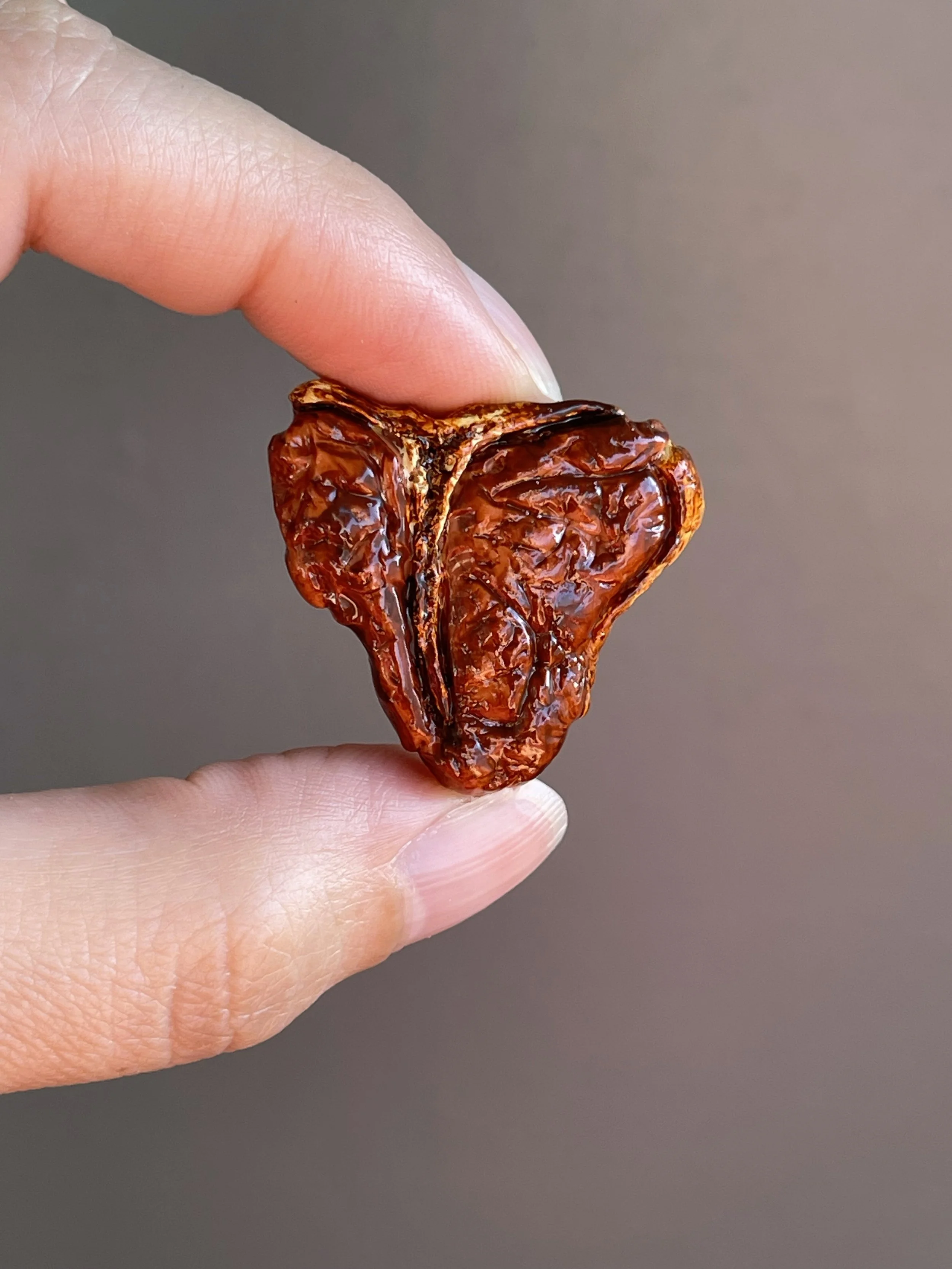 Fingers holding a realistic polymer clay t-bone steak magnet.