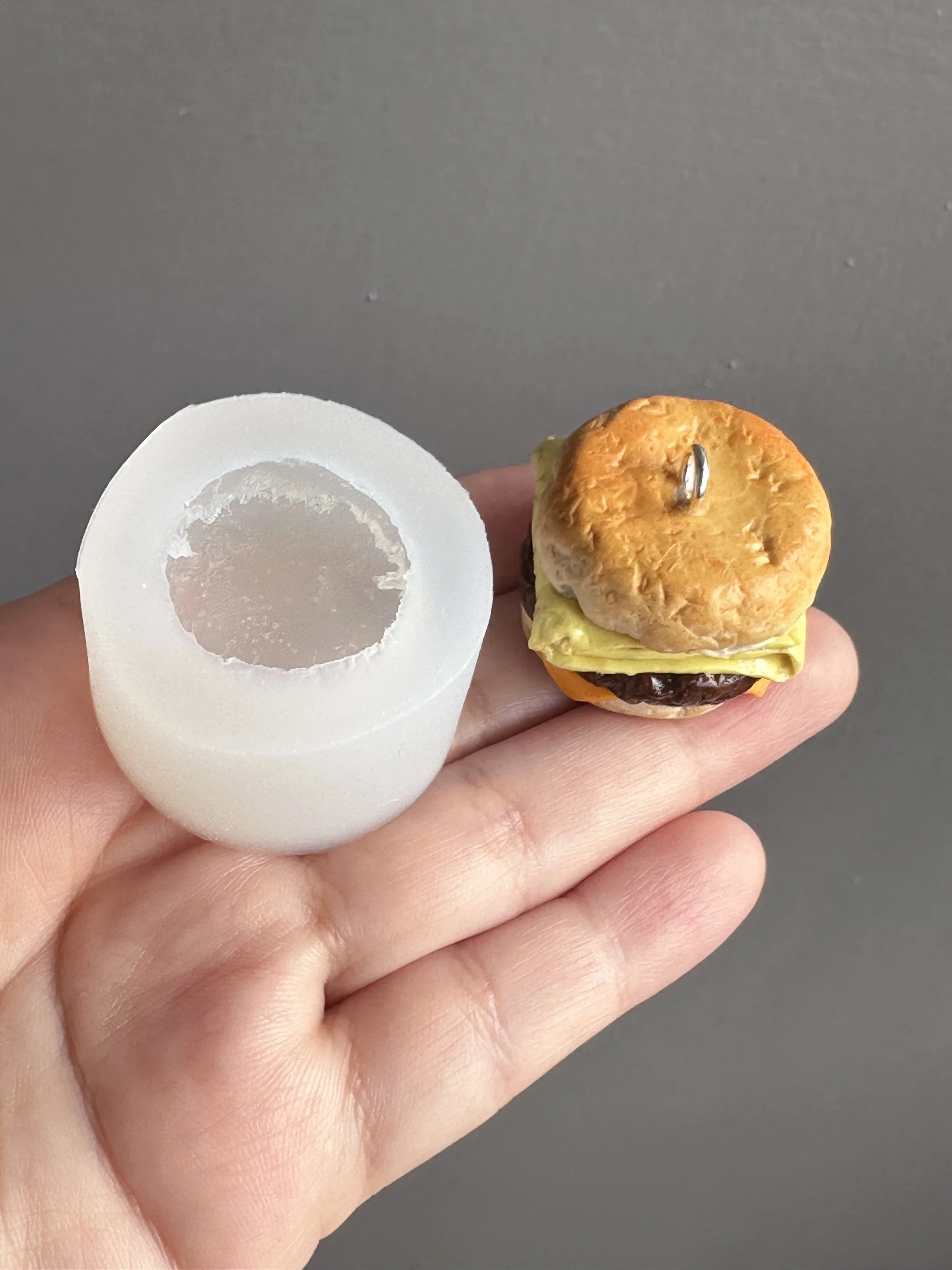 A hand holding a biscuit silicone mold with a sample of the type of biscuit that can be made with the mold next to it.