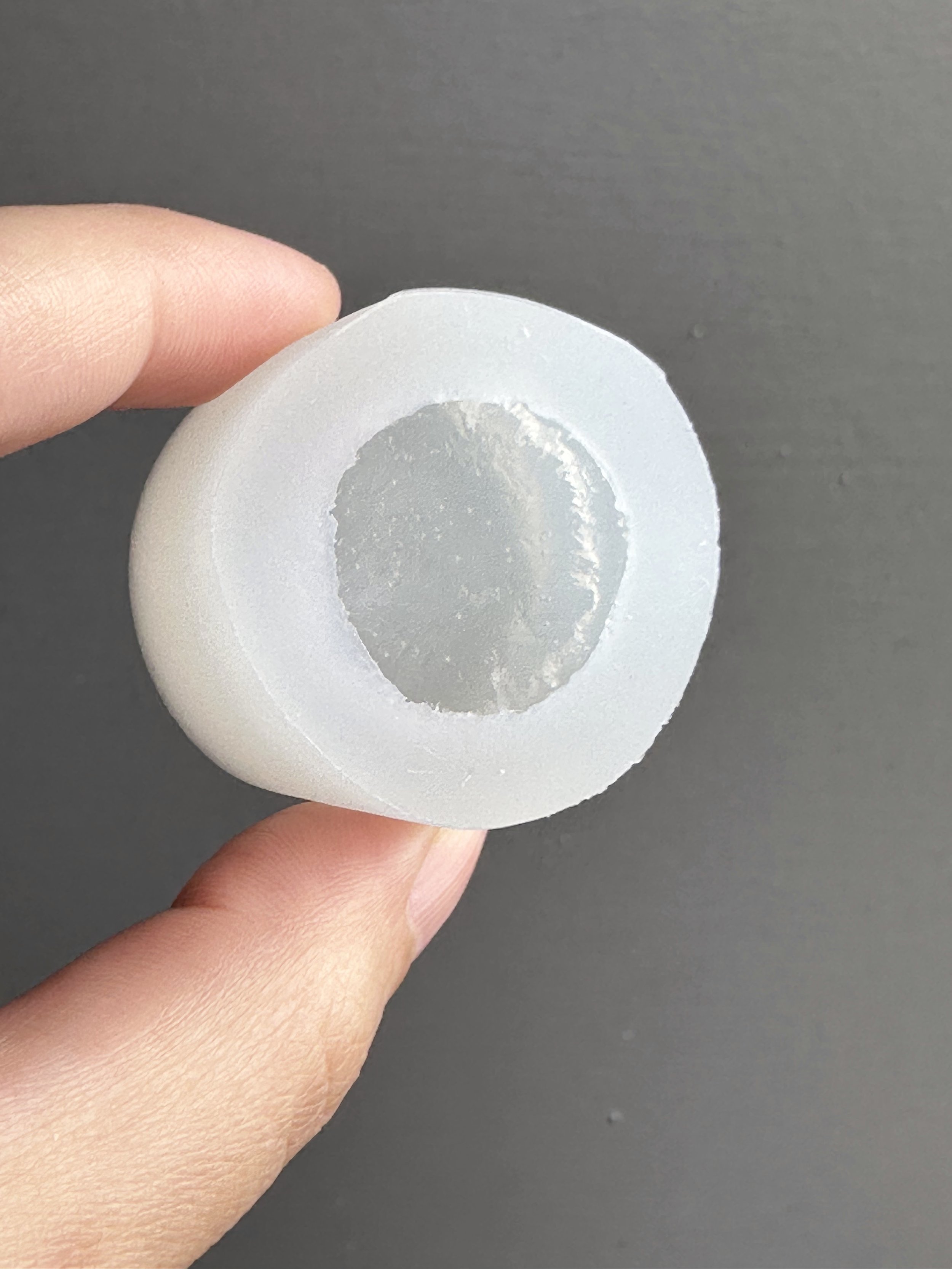 Fingers holding a biscuit silicone mold.