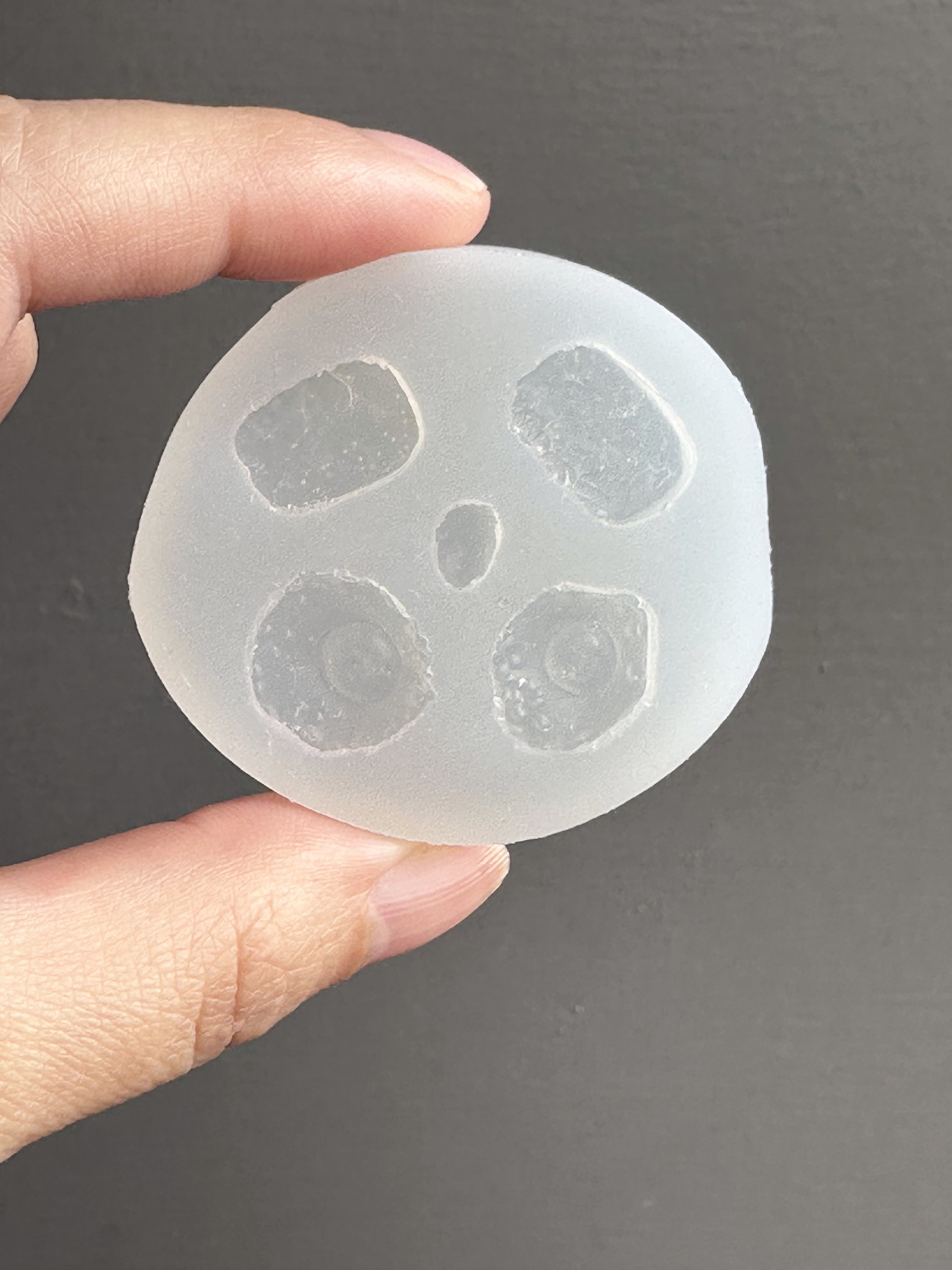 A hand holding a hash browns and fried eggs silicone mold, with a hard boiled egg half element in the center.