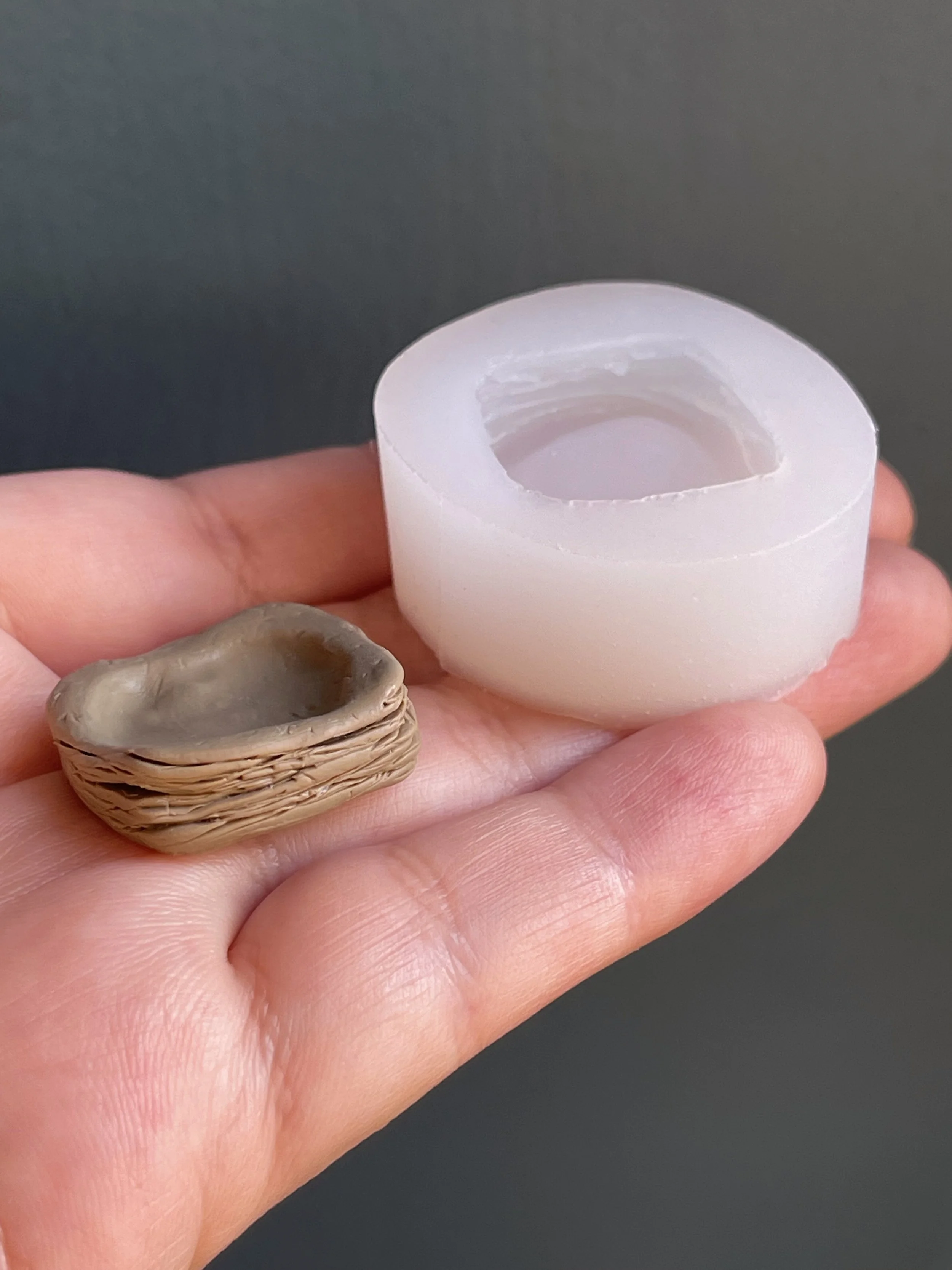 A gray polymer clay silicone master copy next to the clear silicone mold that resulted from it.