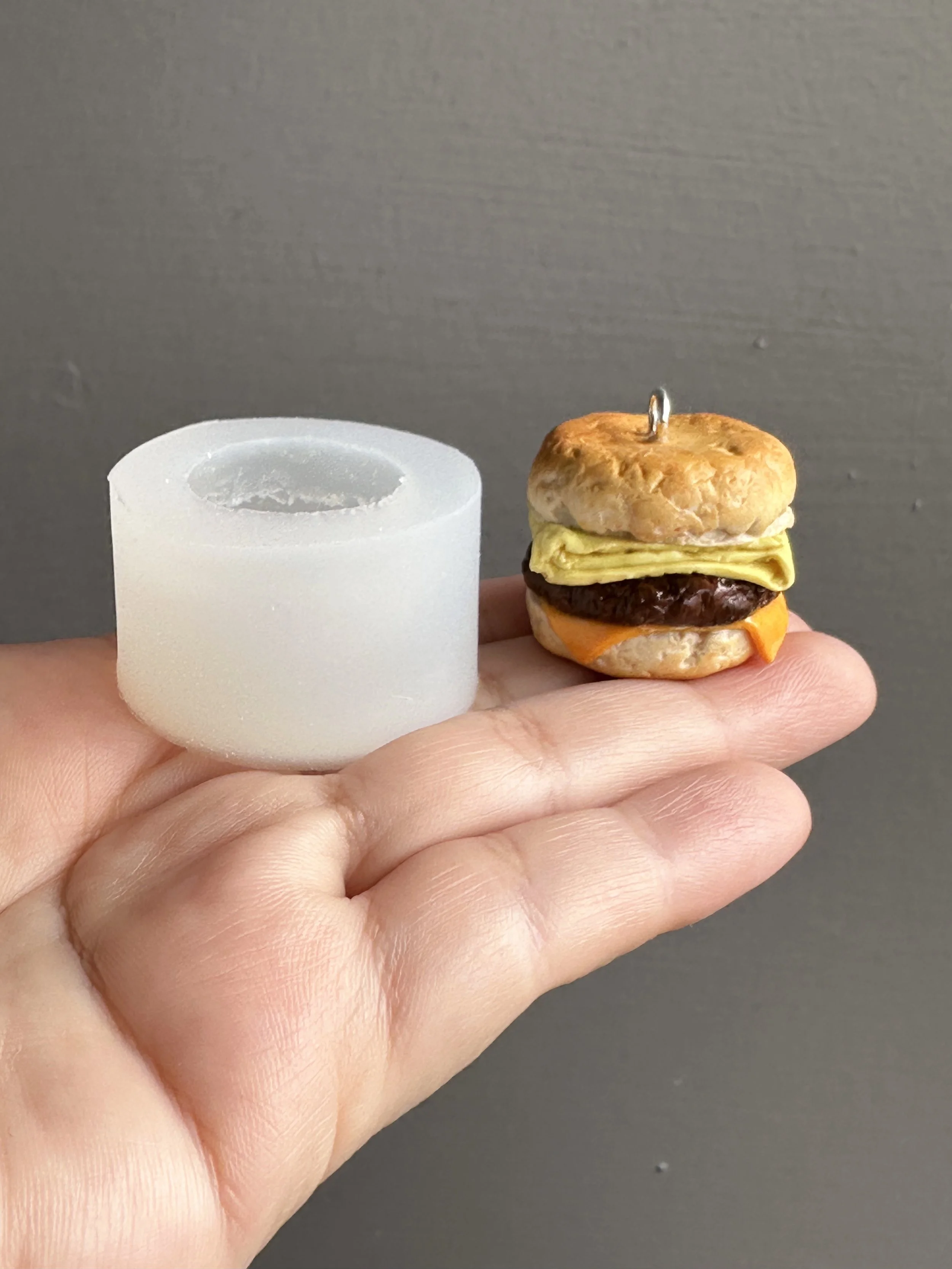 A hand holding a biscuit silicone mold with a sample of the type of biscuit that can be made with the mold next to it.