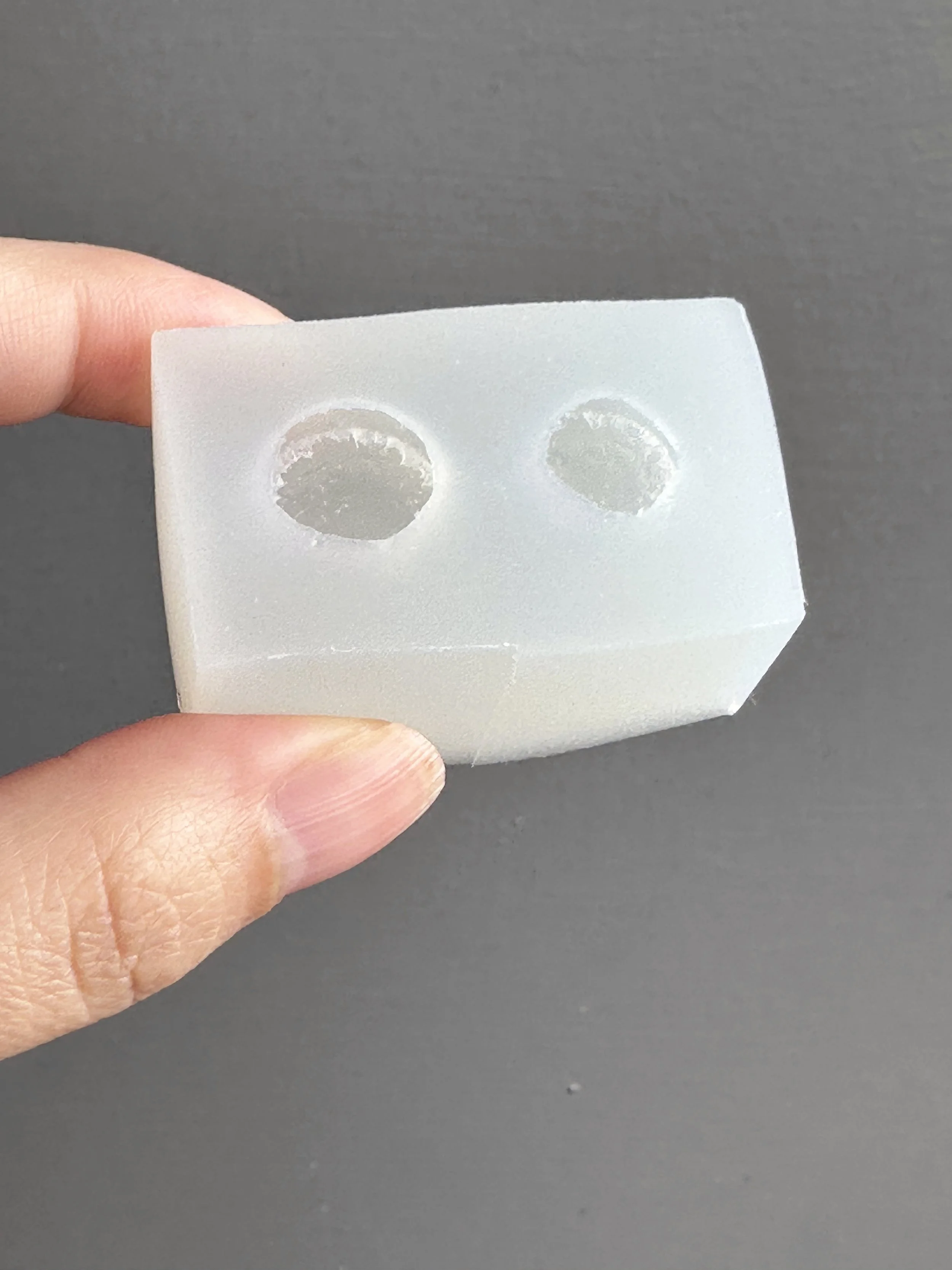 Fingers holding a mini biscuits silicone mold.