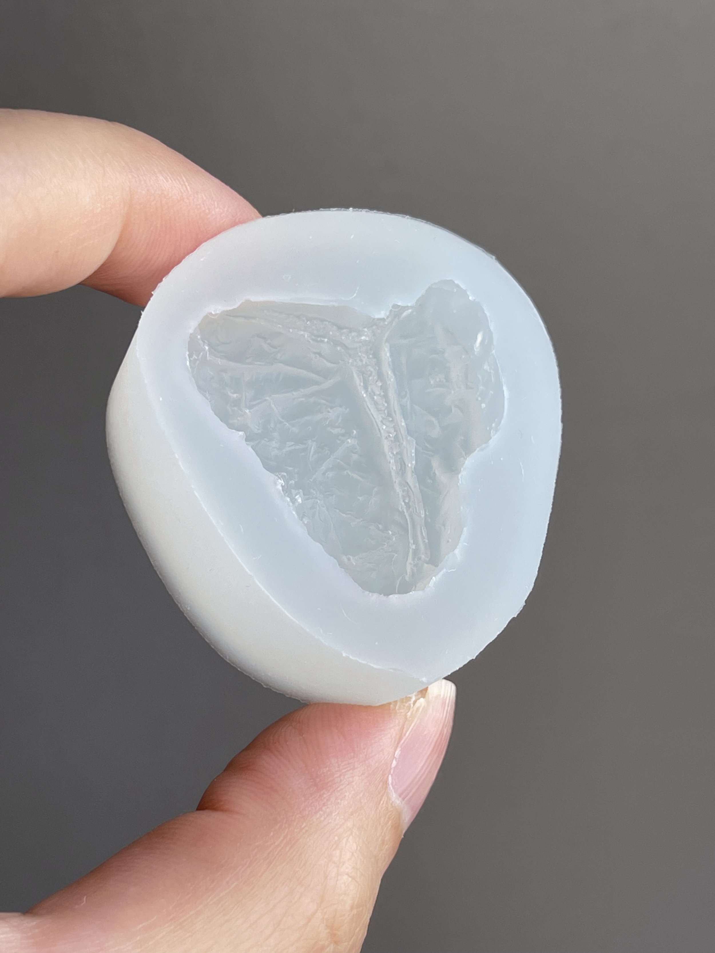 Fingers holding a t-bone steak clear silicone mold.