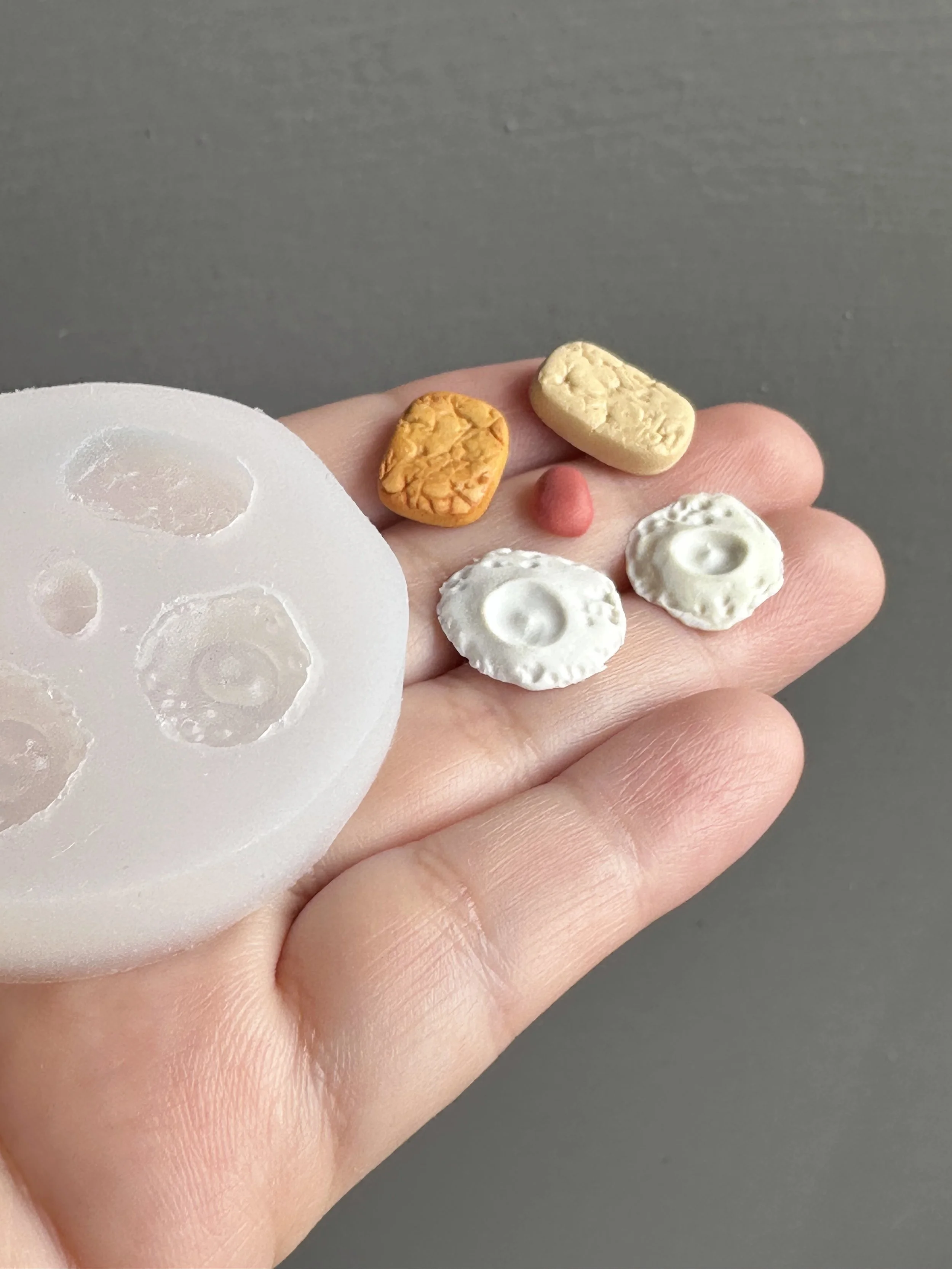 A hand holding a hash browns and eggs silicone mold with the master copies next to it.