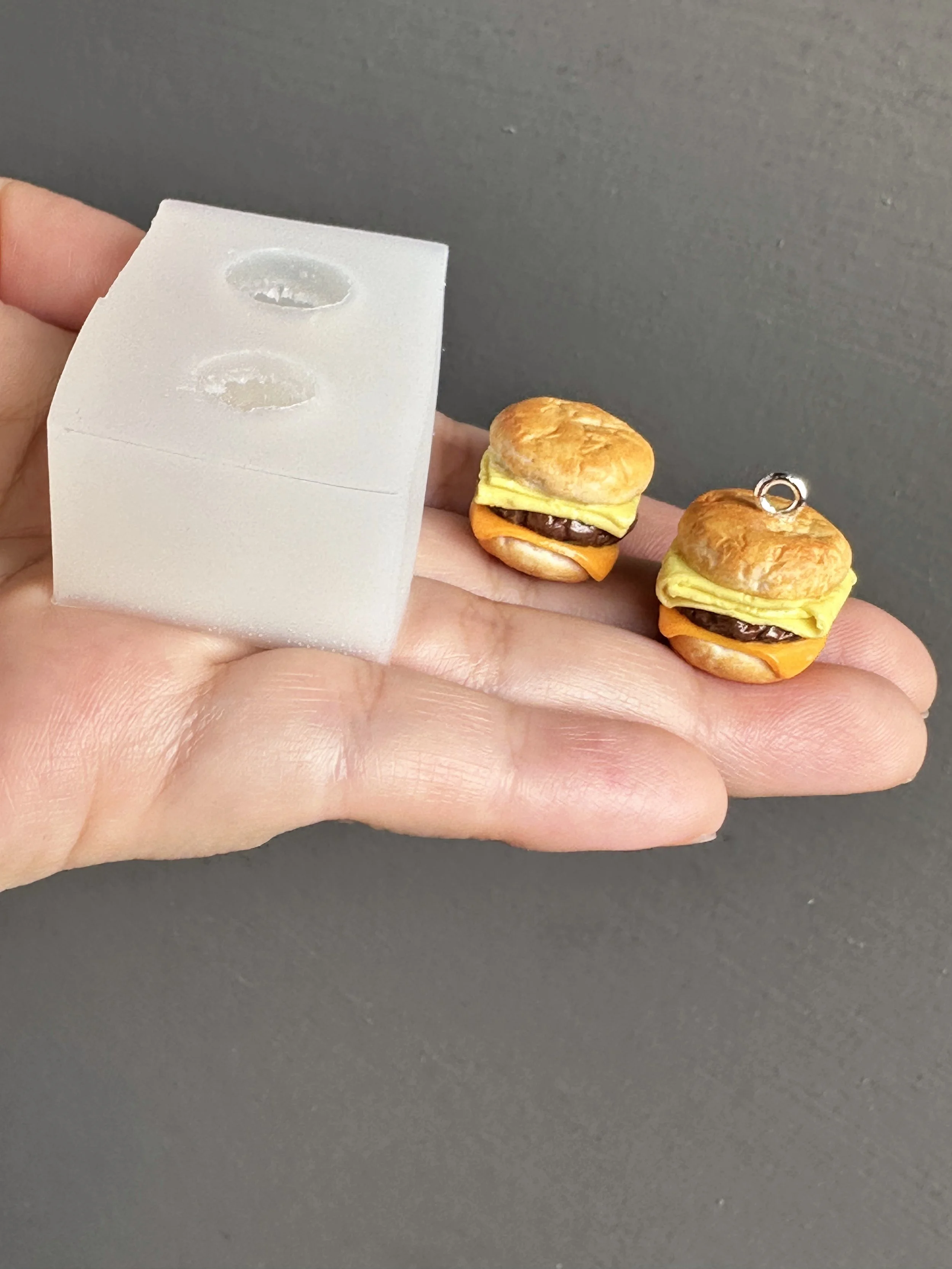 A hand holding a mini biscuits duo silicone mold with samples of the types of biscuits that can be made from the mold.