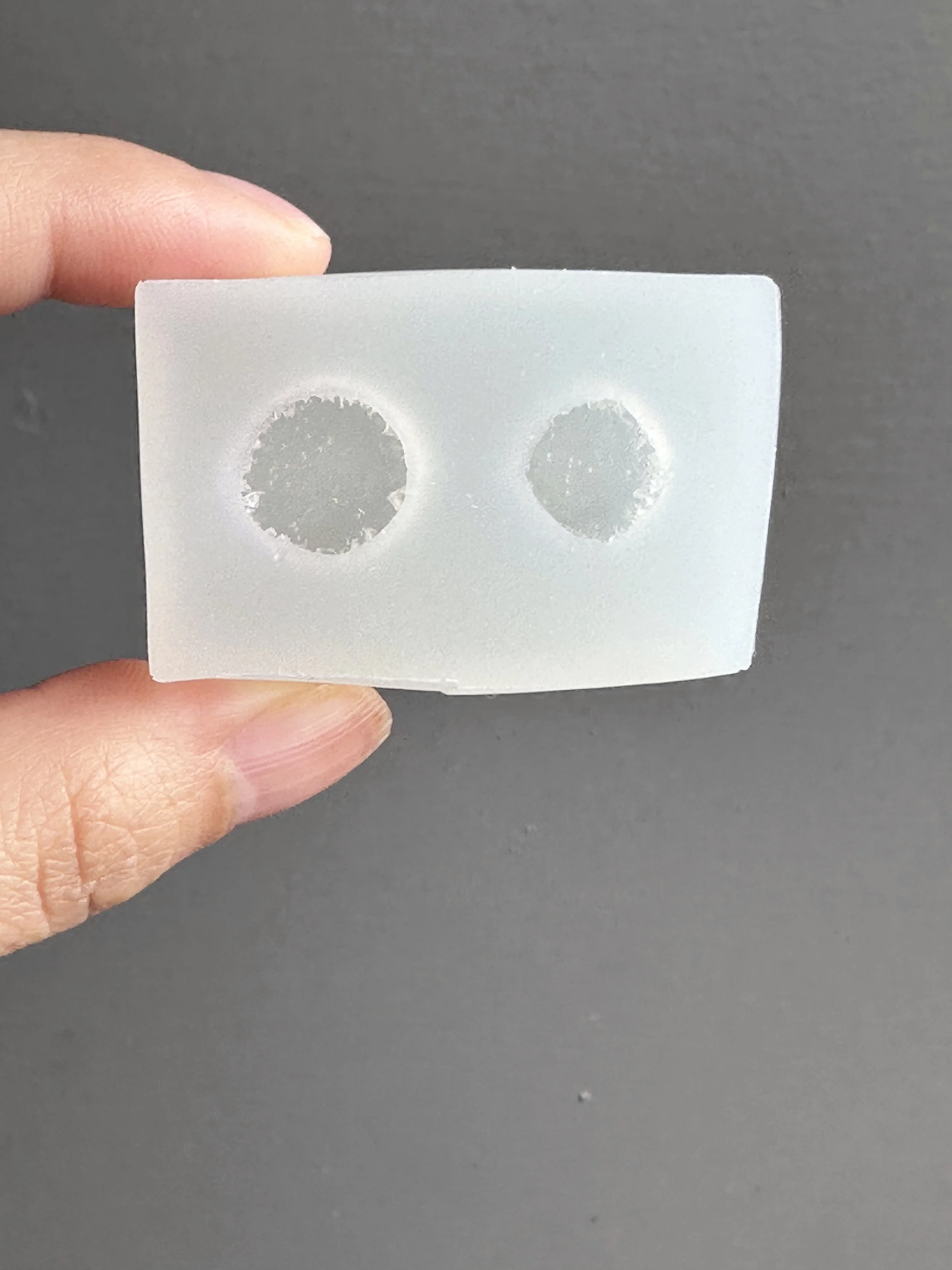 Fingers holding a mini biscuits silicone mold.
