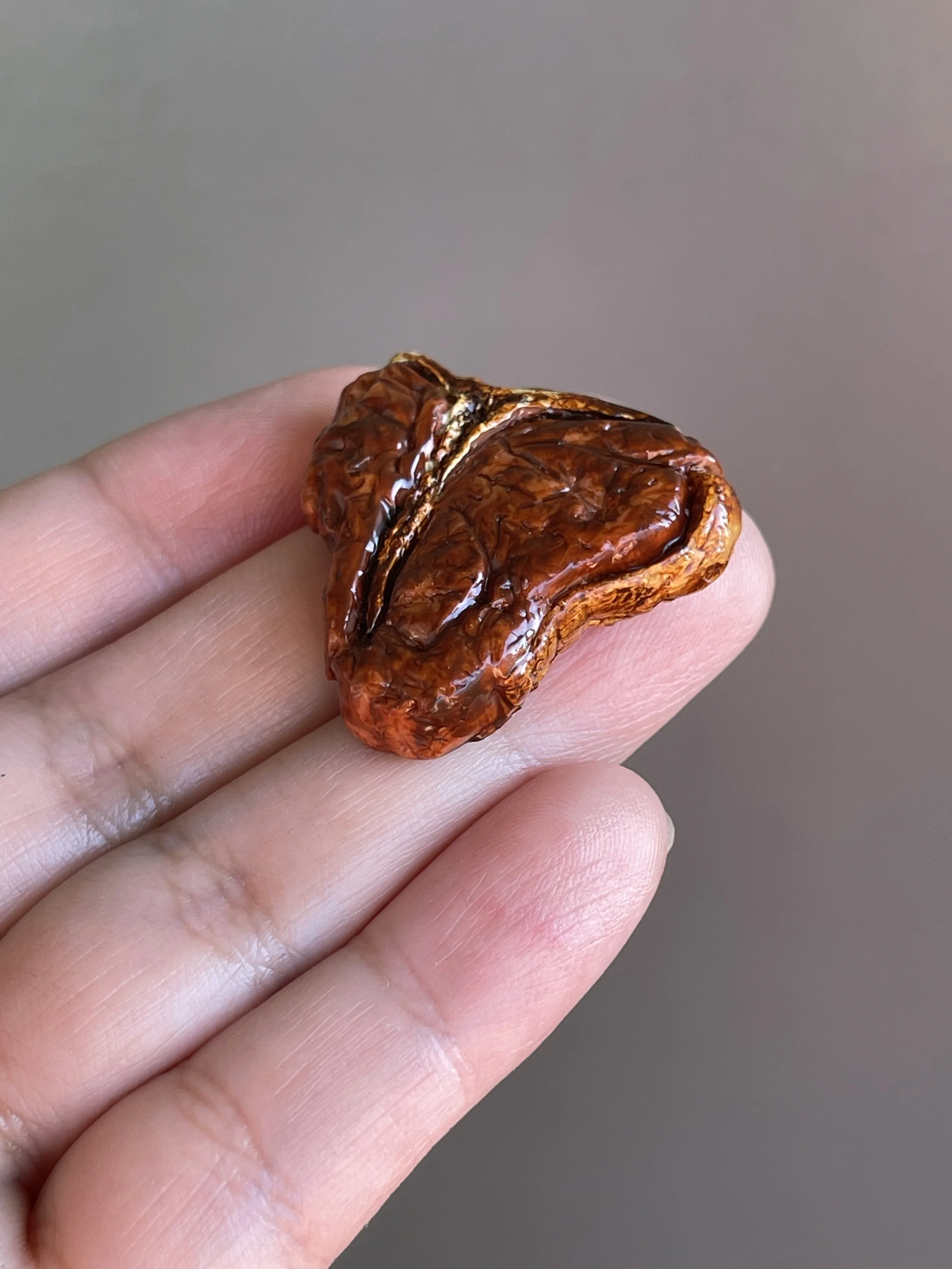 A hand holding a realistic polymer clay t-bone steak magnet.