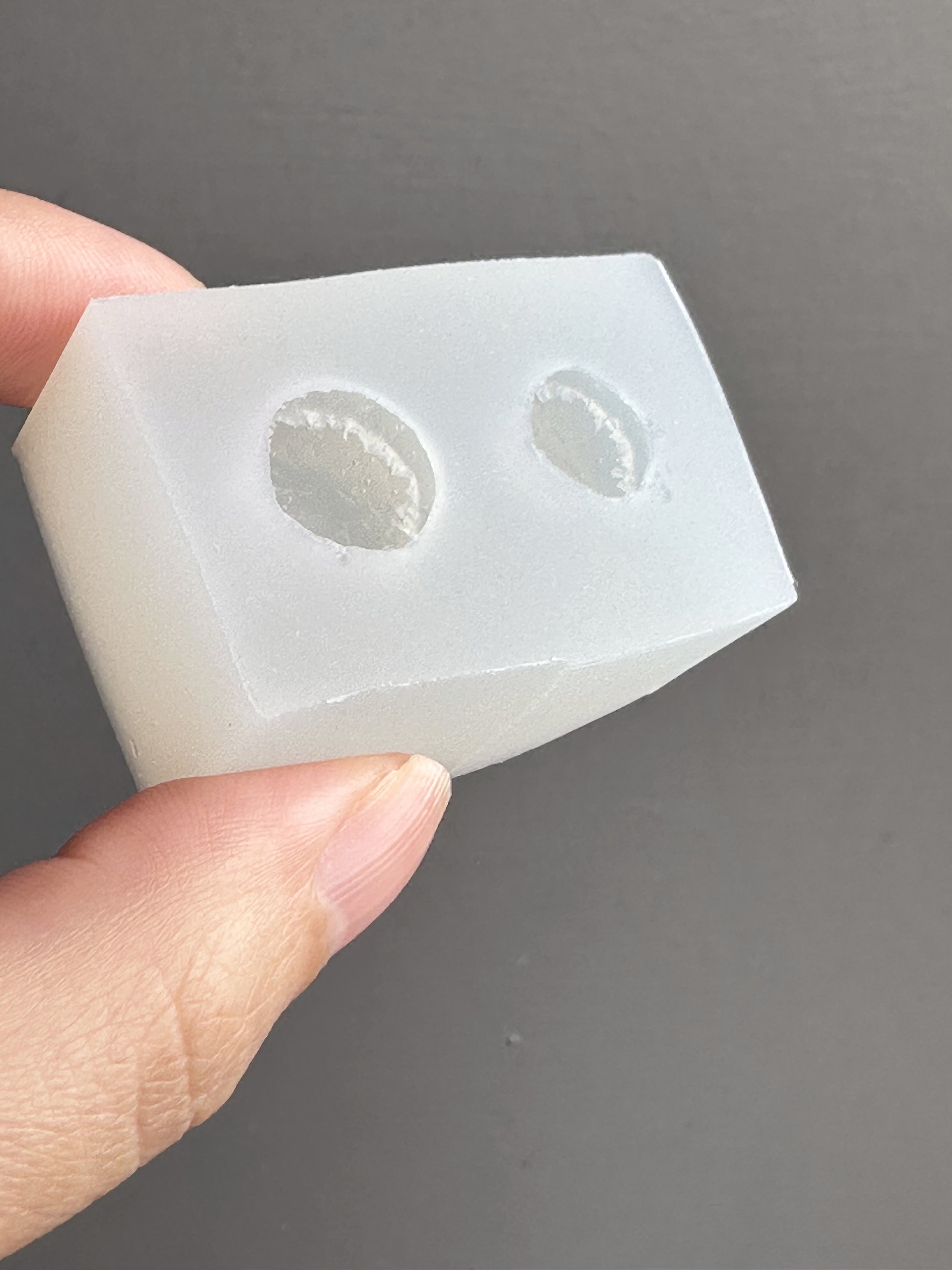 Fingers holding a mini biscuits silicone mold.