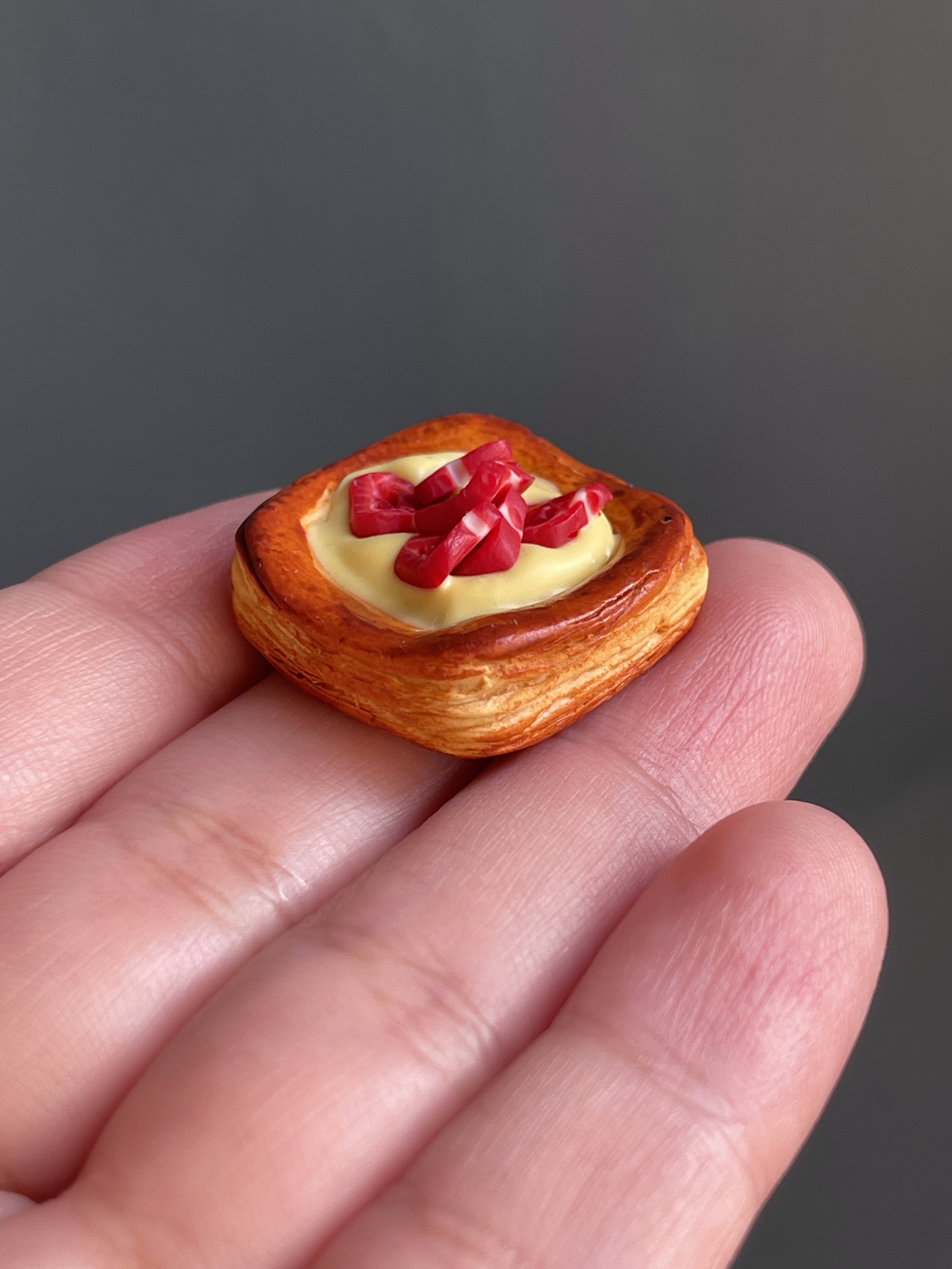 A polymer clay danish with yellow cream and strawberry slices.