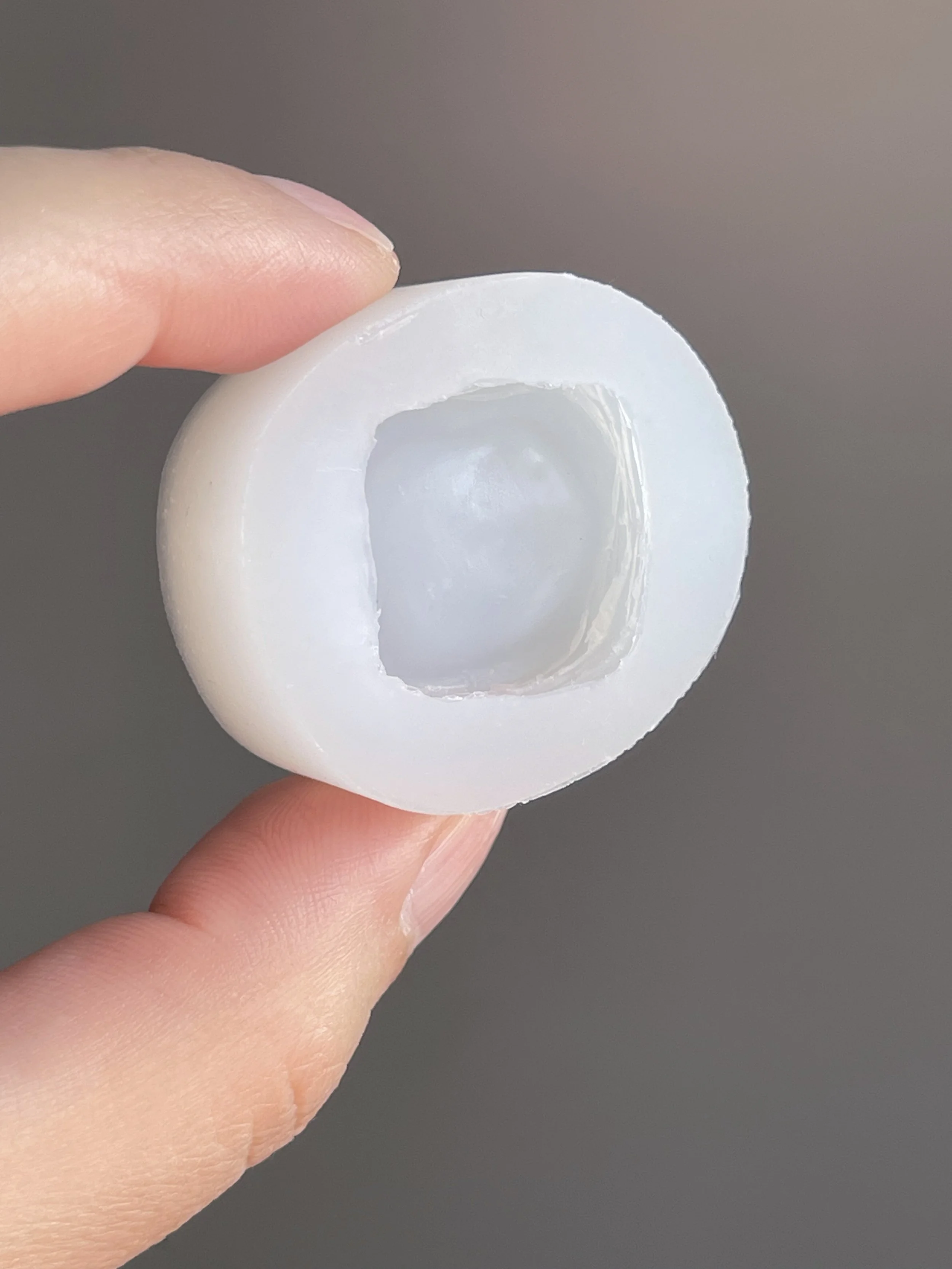 Fingers holding a clear danish pastry silicone mold.