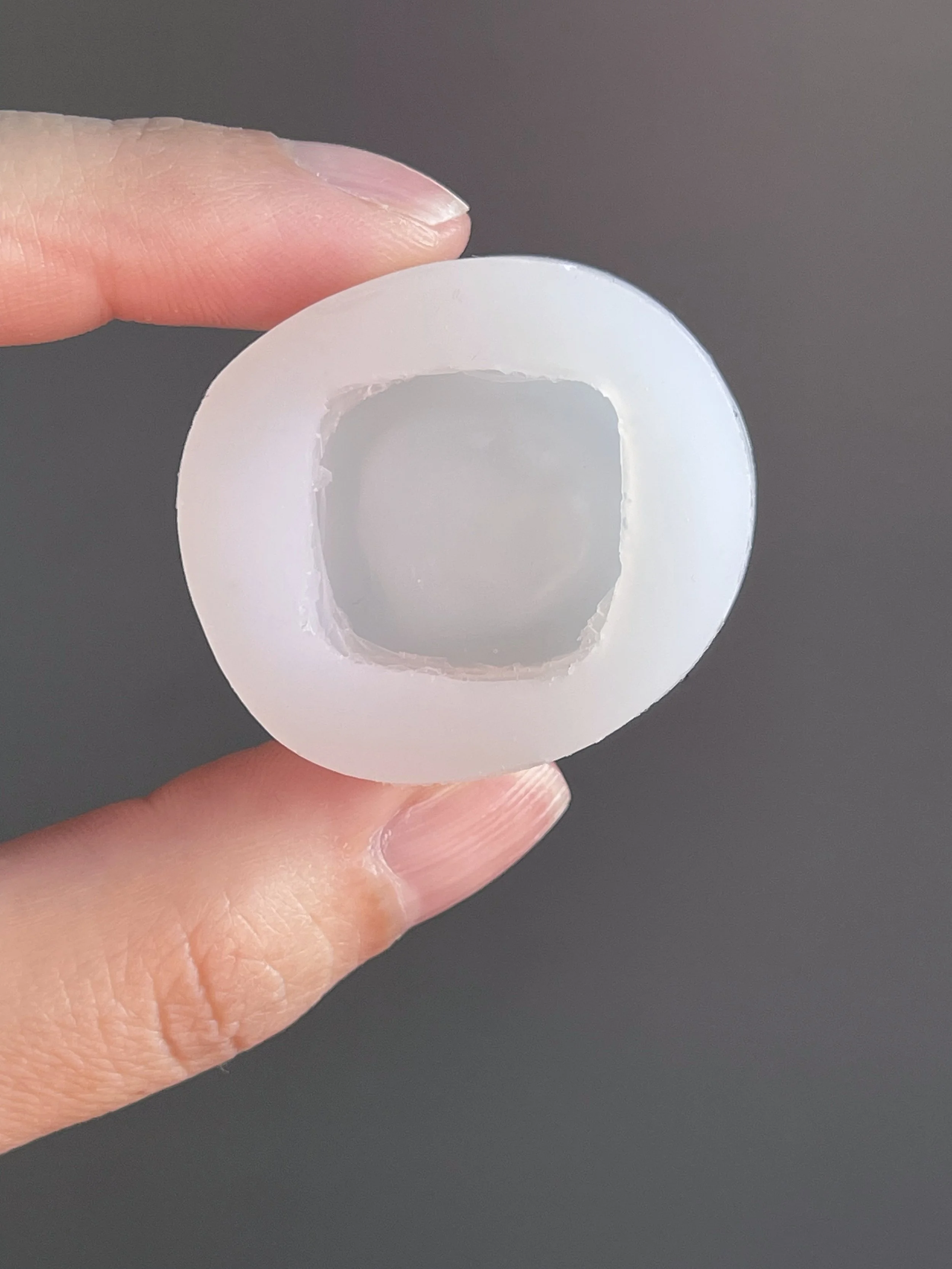 Fingers holding a clear danish pastry silicone mold.