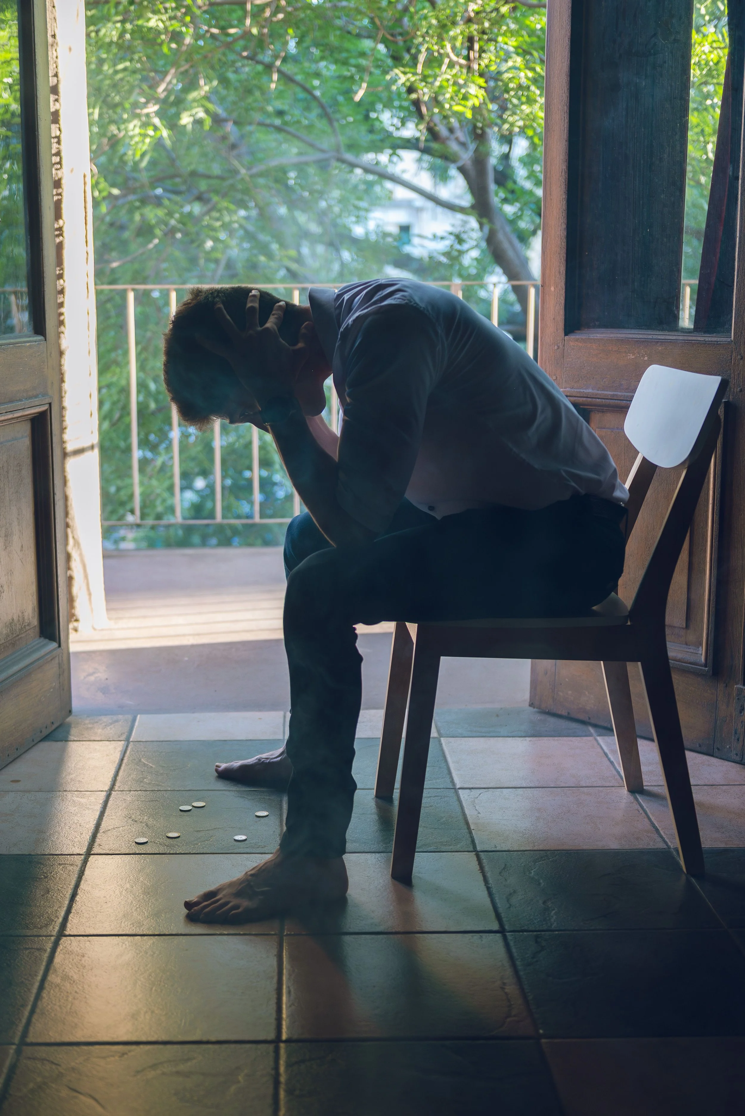 Mann sitzt allein mit gesenktem Kopf auf einem Stuhl, Symbolbild für Depression und psychische Belastung bei Männern