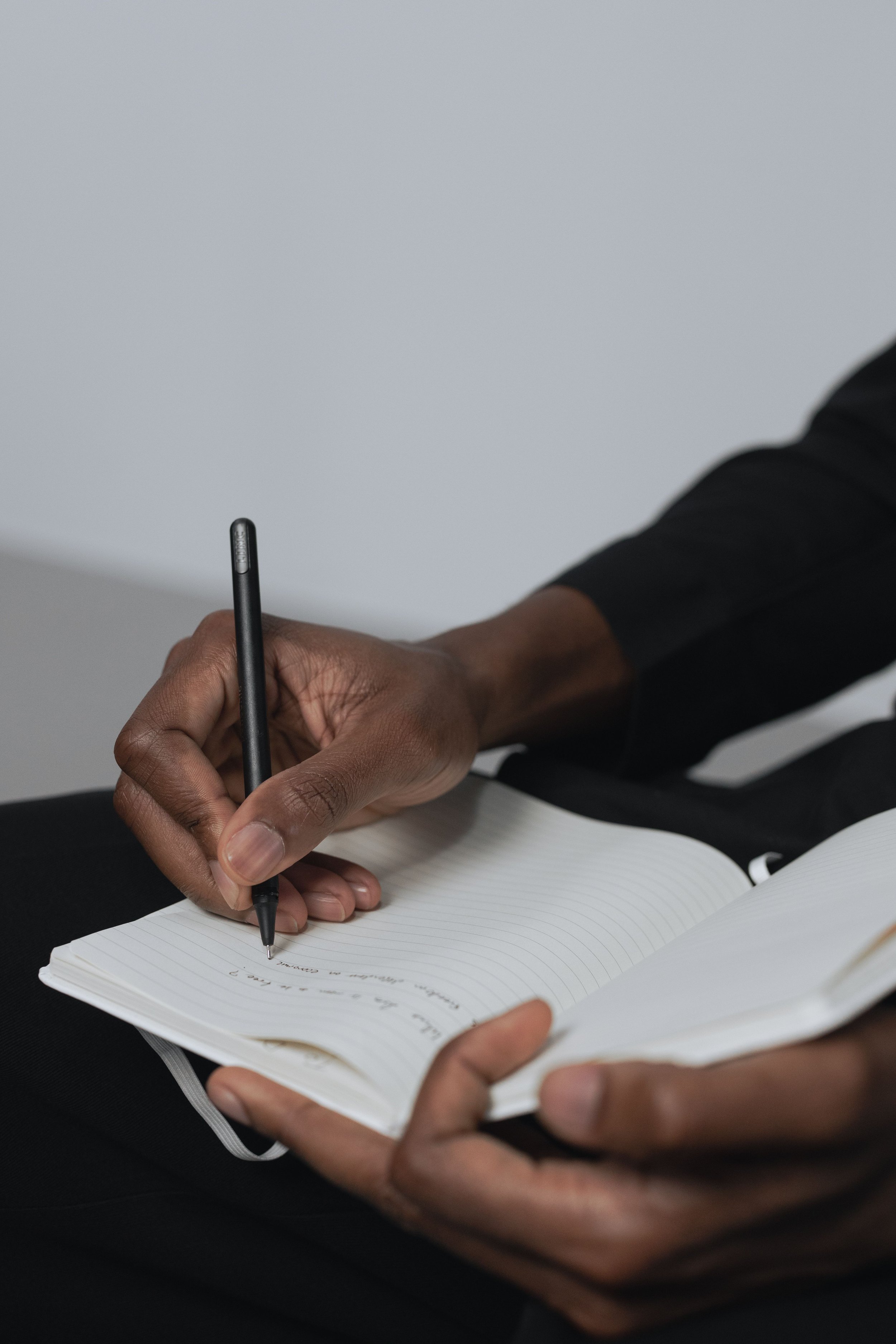 Person schreibt mit Stift in ein liniertes Notizbuch, Journaling als Methode zur Selbstreflexion und emotionalen Gesundheit