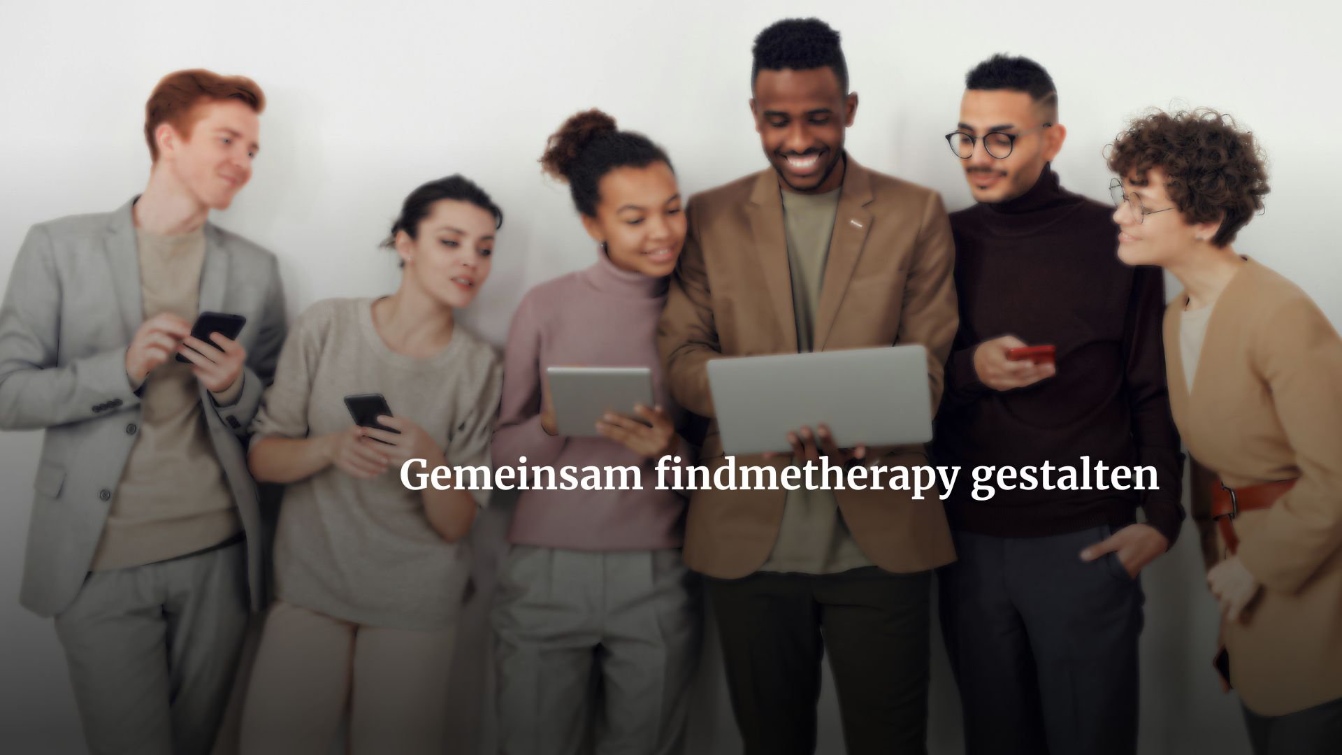 Eine Gruppe von Menschen steht zusammen vor einer weißen Wand und schaut auf einen Laptop. Sie lachen und sind interessiert an der Präsentation.