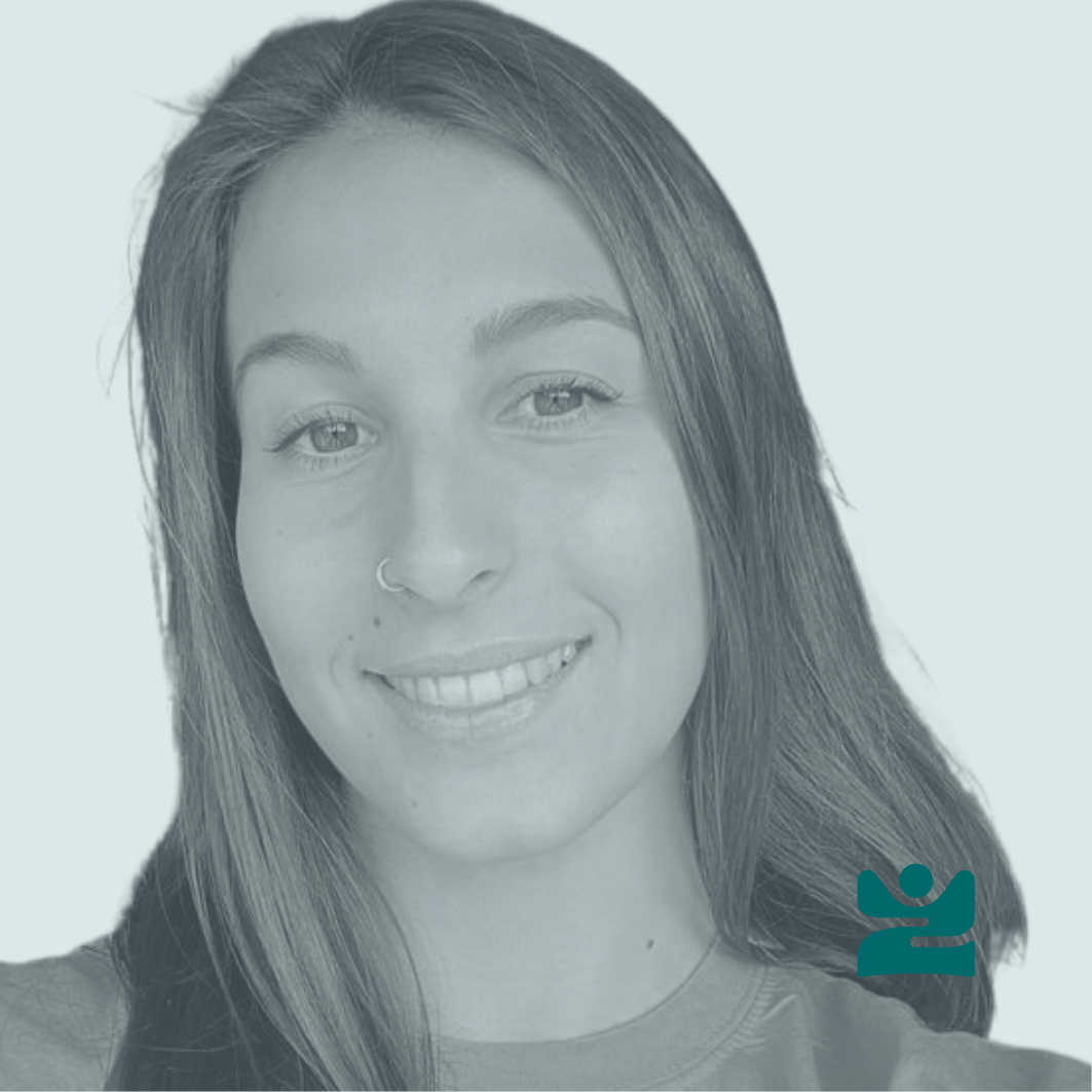 Ritratto di una donna sorridente con capelli lunghi e chiari, con un naso a cerchio e una maglietta, su uno sfondo chiaro.