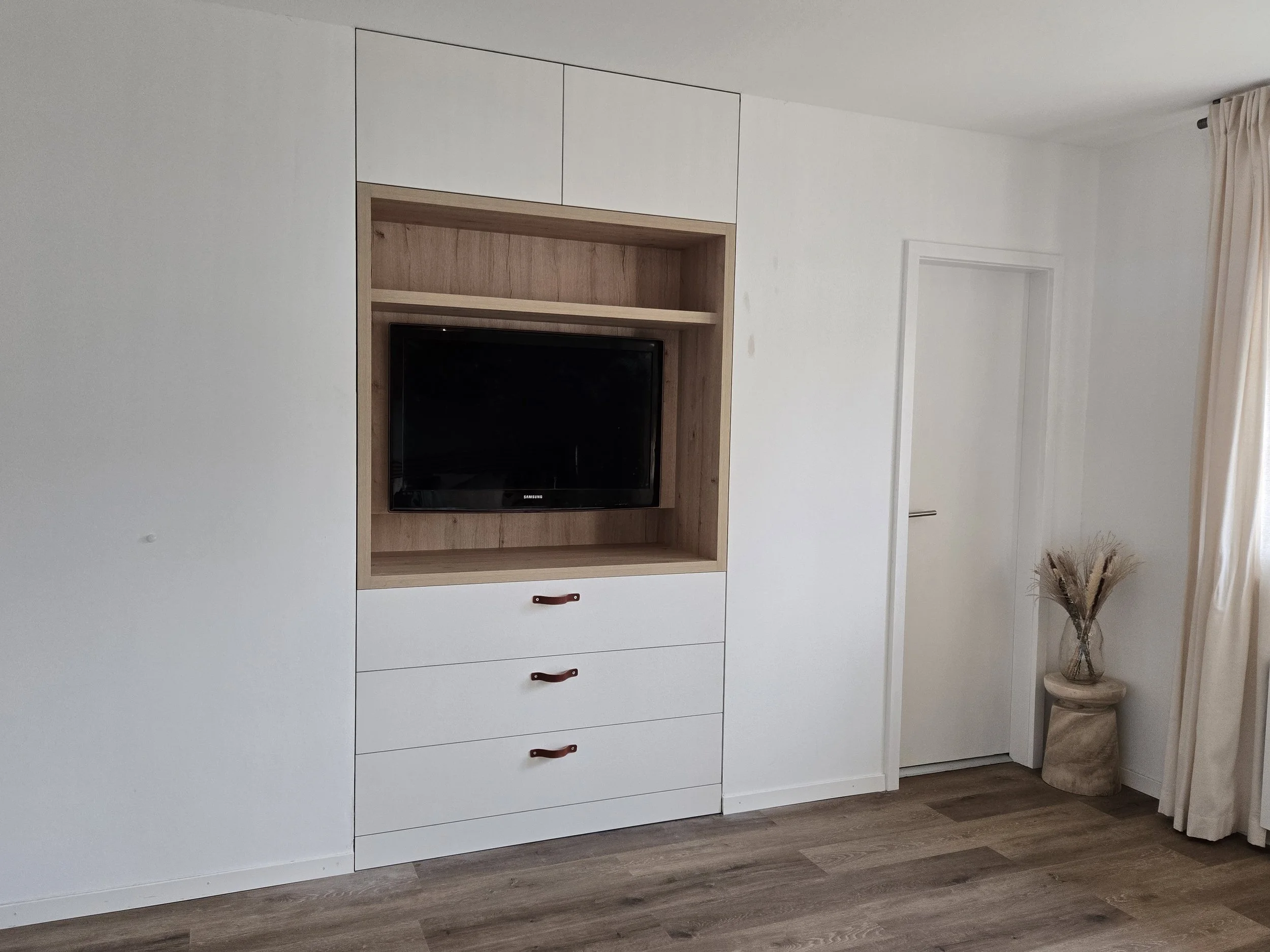 Meuble TV intégré avec commode inférieure, rangements supérieurs, poignées lanières en cuir. Stratifié couleur chêne et blanc, travail artisanal, ébénisterie Sauthier