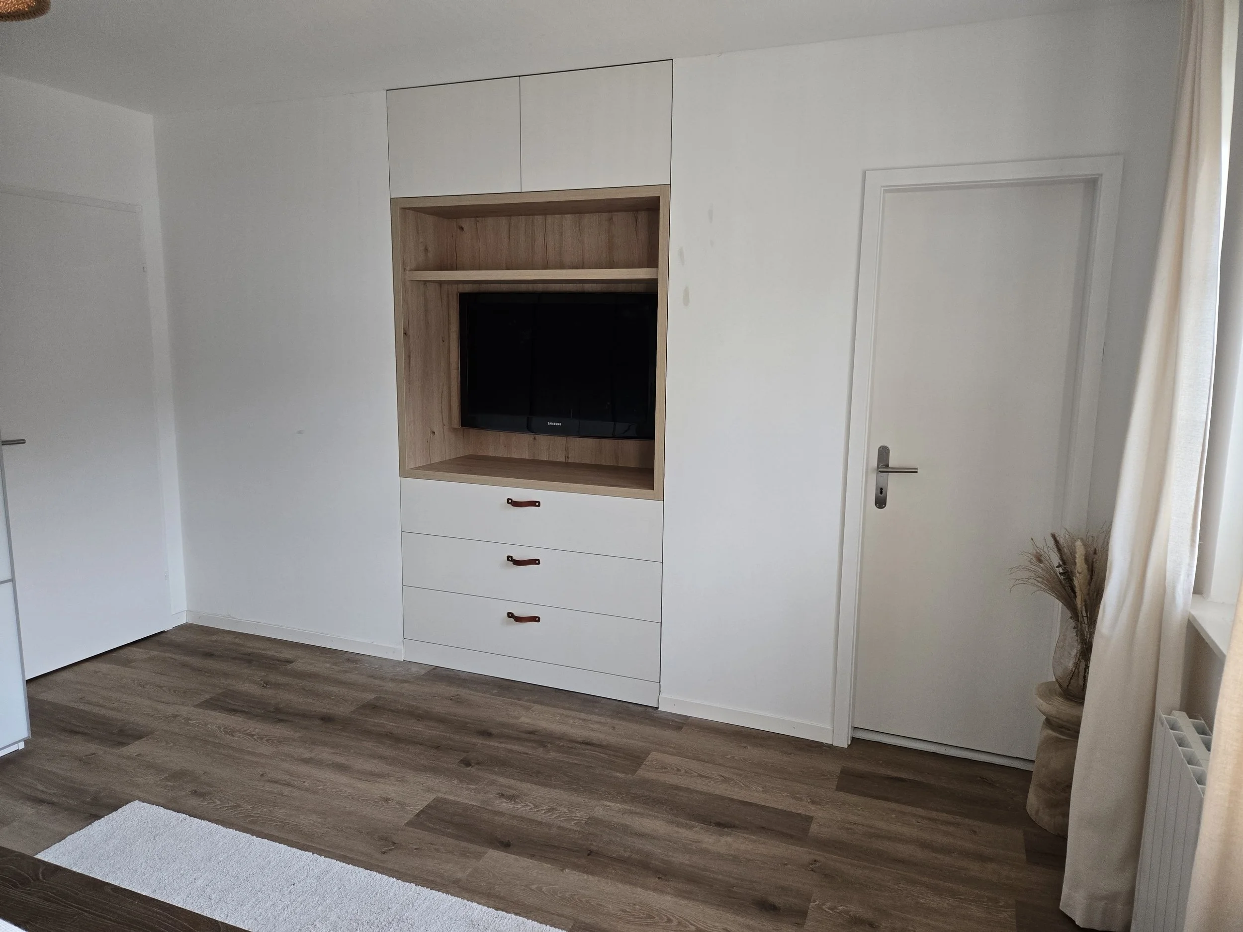 Meuble TV intégré avec commode inférieure, rangements supérieurs, poignées lanières en cuir. Stratifié couleur chêne et blanc, travail artisanal, ébénisterie Sauthier