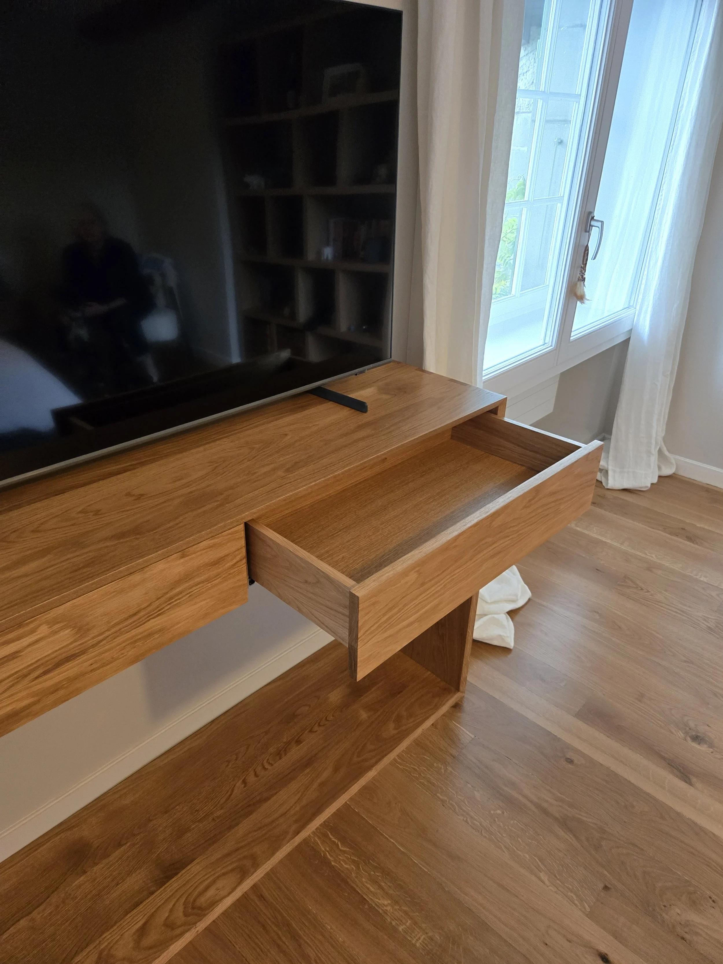 Meuble TV en chêne massif avec queues droites et raccord à l'onglet. Fabrication artisanale sur mesures pour inclure les prises électriques dans l'espace sous les tiroirs. Dos amovible à peindre pour cacher les prises. Tiroirs en chêne massif. Créden