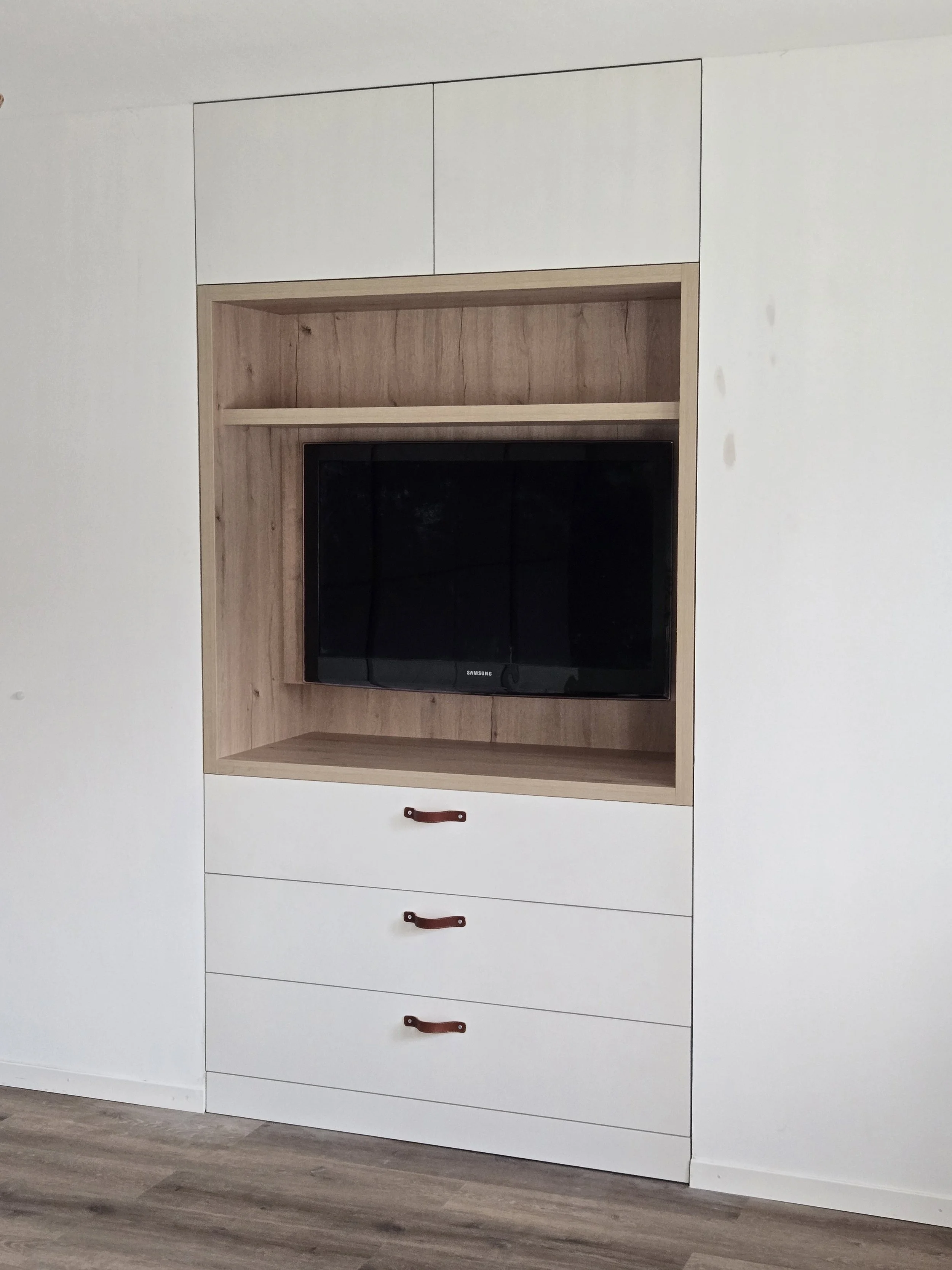 Meuble TV intégré avec commode inférieure, rangements supérieurs, poignées lanières en cuir. Stratifié couleur chêne et blanc, travail artisanal, ébénisterie Sauthier