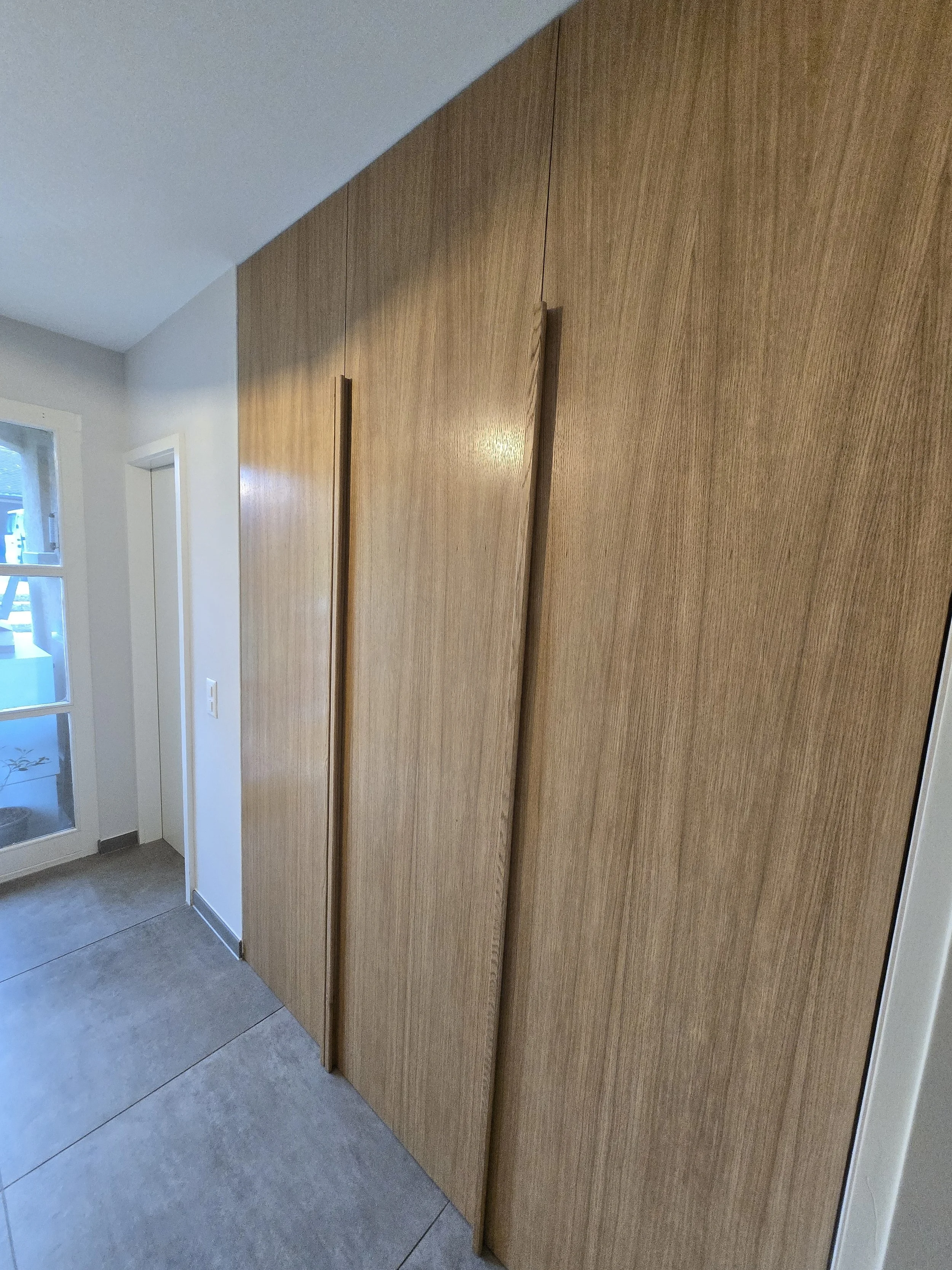 Dressing hall d'entrée, portes sol plafond plaquées en chêne, poignée en chêne massif, intérieur blanc avec tiroirs, penderies, lifts pour habits et chaussures, travail artisanal, ébénisterie Sauthier