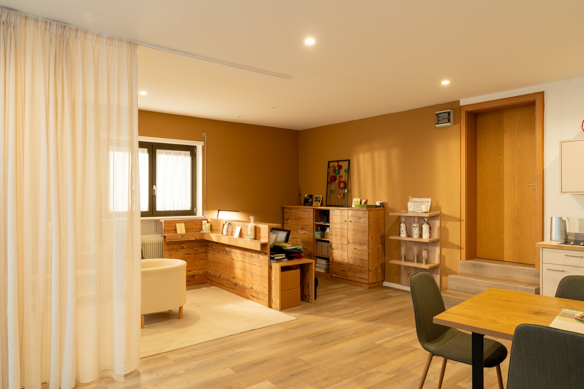 Gemütliches Büro von Rudi Sampt mit Holzmöbeln, Vorhängen, Tisch und Stühlen, warmem Licht, und dekorativen Details in einem modernen Stil.
