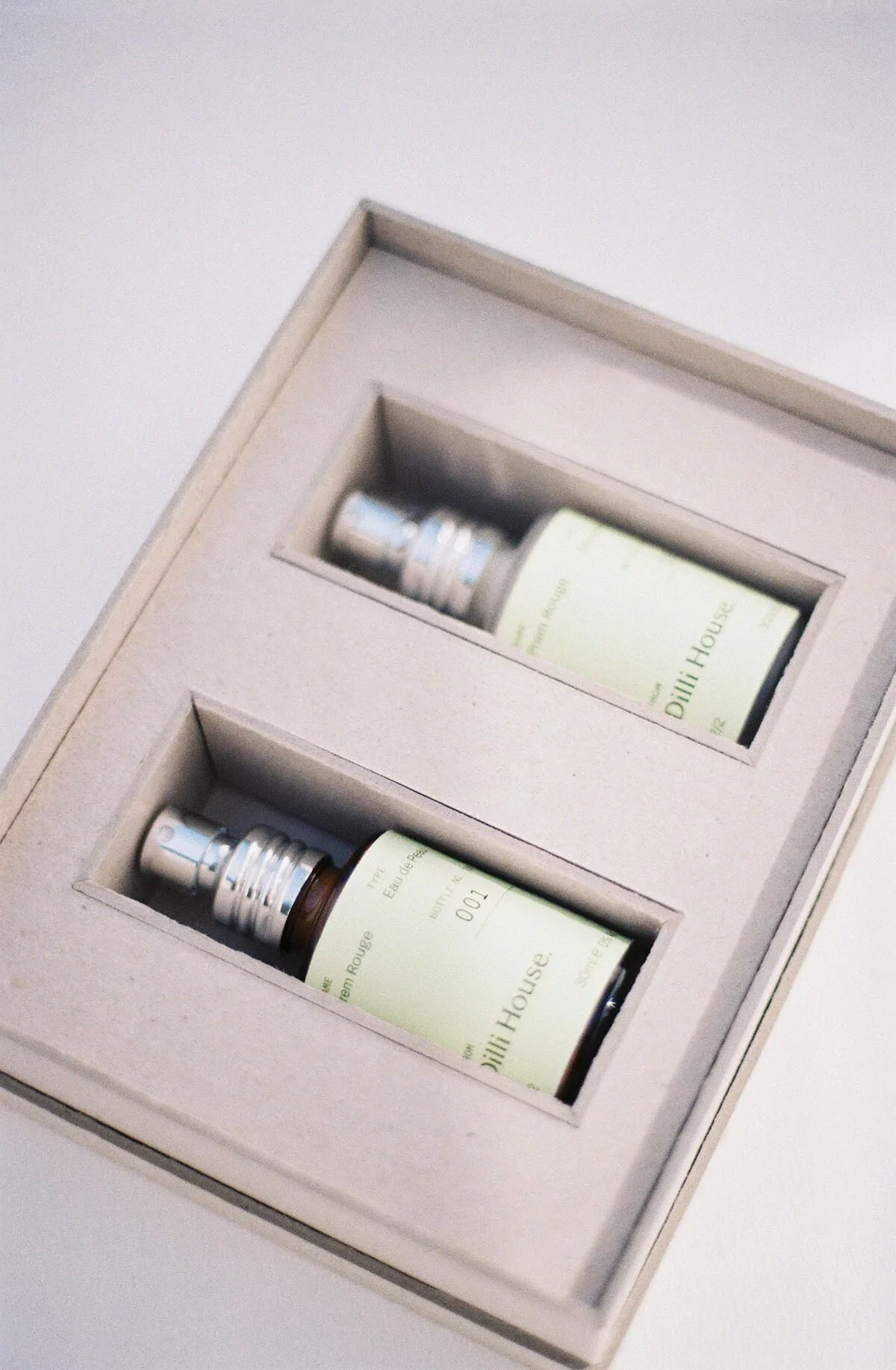 Two small bottles of perfume in a beige box with foam inserts.