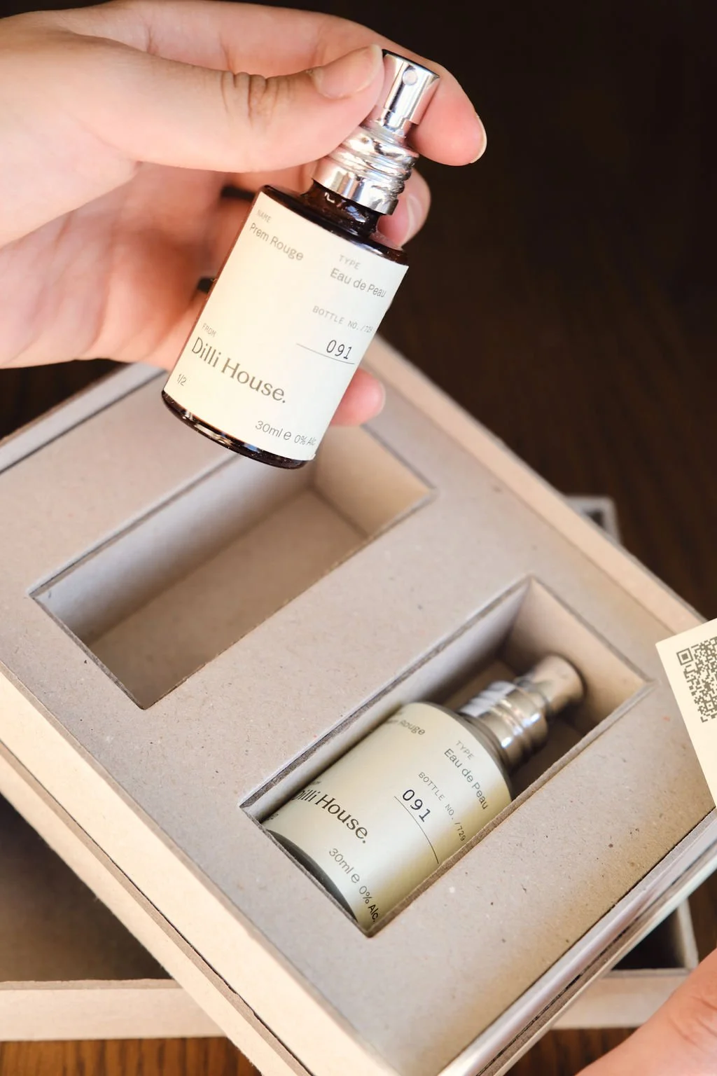 A hand lifting a Prem Rouge bottle out of the presentation box