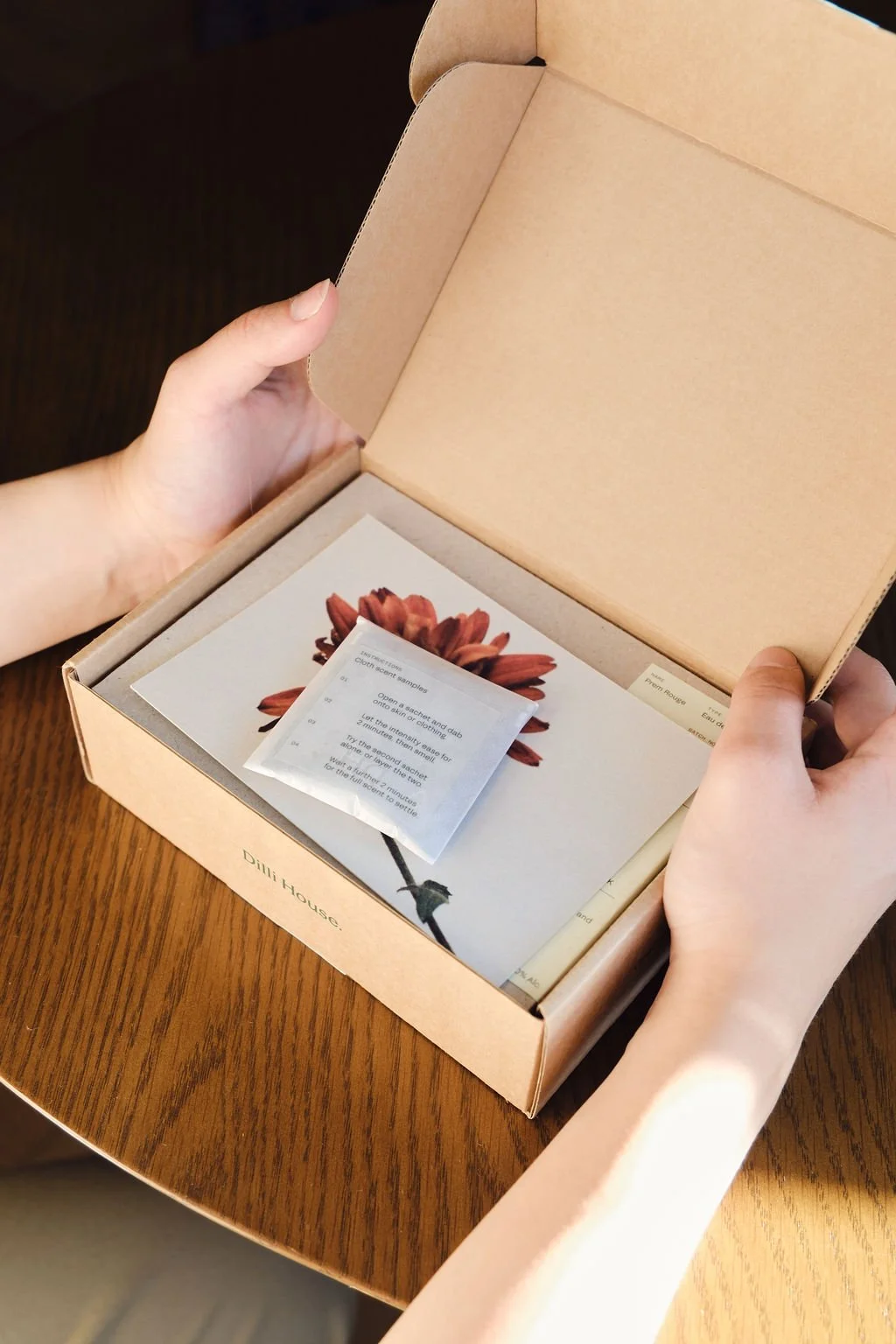 Hands opening the Dilli House mailing box to reveal the card and print inside