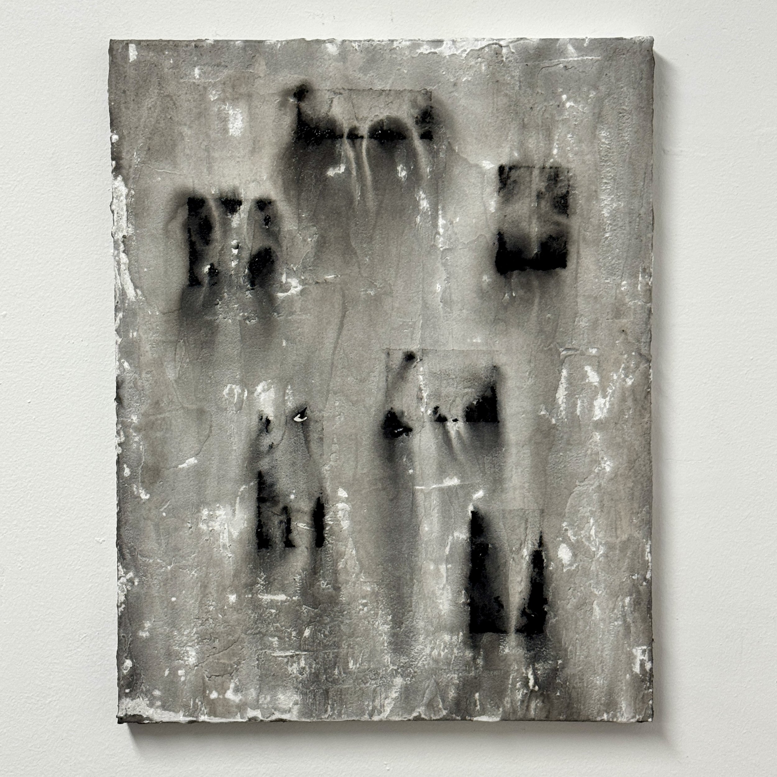 A black and white abstract artwork on a canvas or paper, featuring irregular shapes and textures with a mottled appearance.
