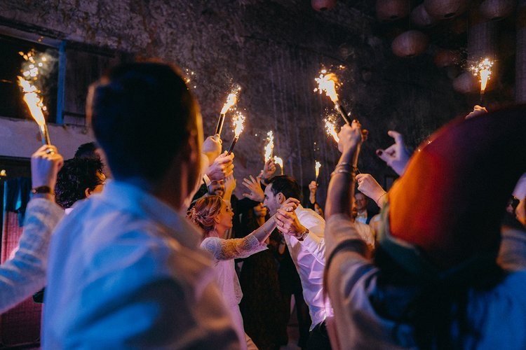 Groupe de personnes dansant avec des cierges magiques lors d'une fête nocturne.