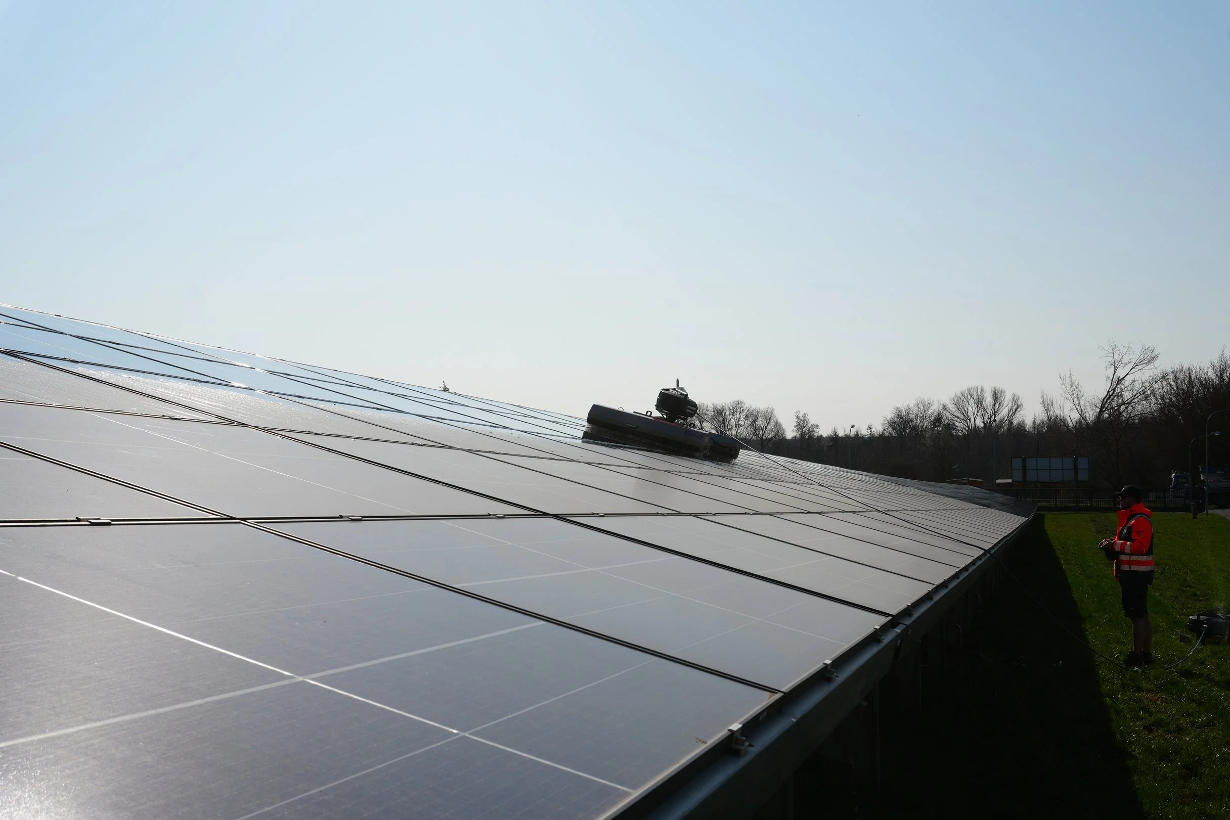 Strauer-Fachkraft_steht_ vor_einem_Solarpark_der_mit_Robotertechnik_gereinigt_wird.png