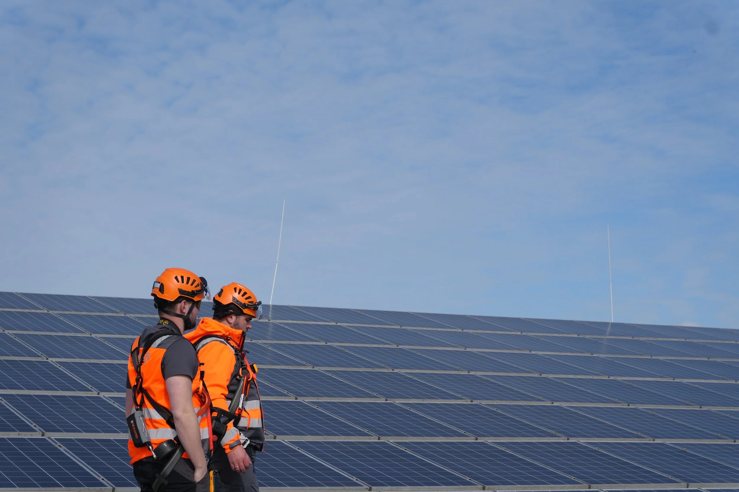 Zwei STRAUER-Solarreiniger stehen in vollständiger Arbeitsschutzausrüstung vor einer großen Solaranlage. Das erfahrene Team sorgt mit professioneller Ausrüstung für eine sichere und fachgerechte Solarreinigung.