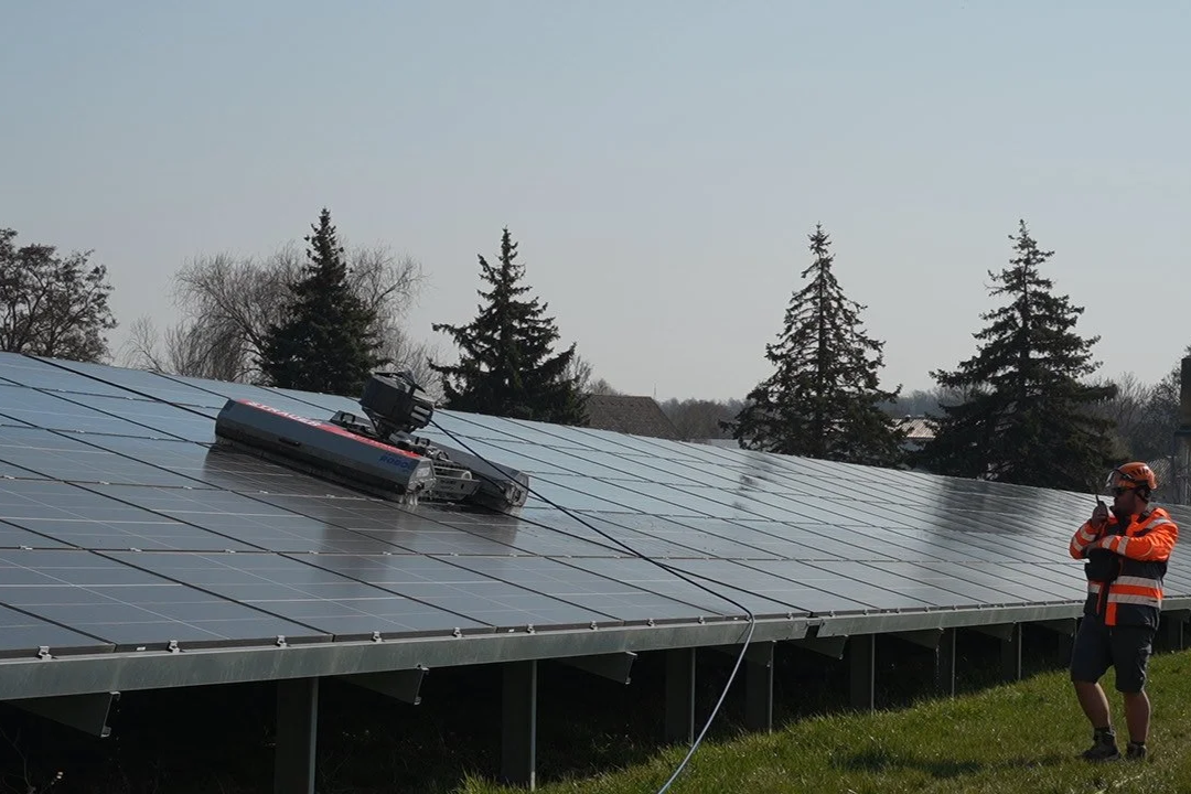 Ein STRAUER-Reinigungsmitarbeiter bedient einen Solarreinigungsroboter auf einer Freiflächenanlage. Die moderne Reinigungstechnik ermöglicht eine effiziente und schonende Reinigung großer Solarparks.