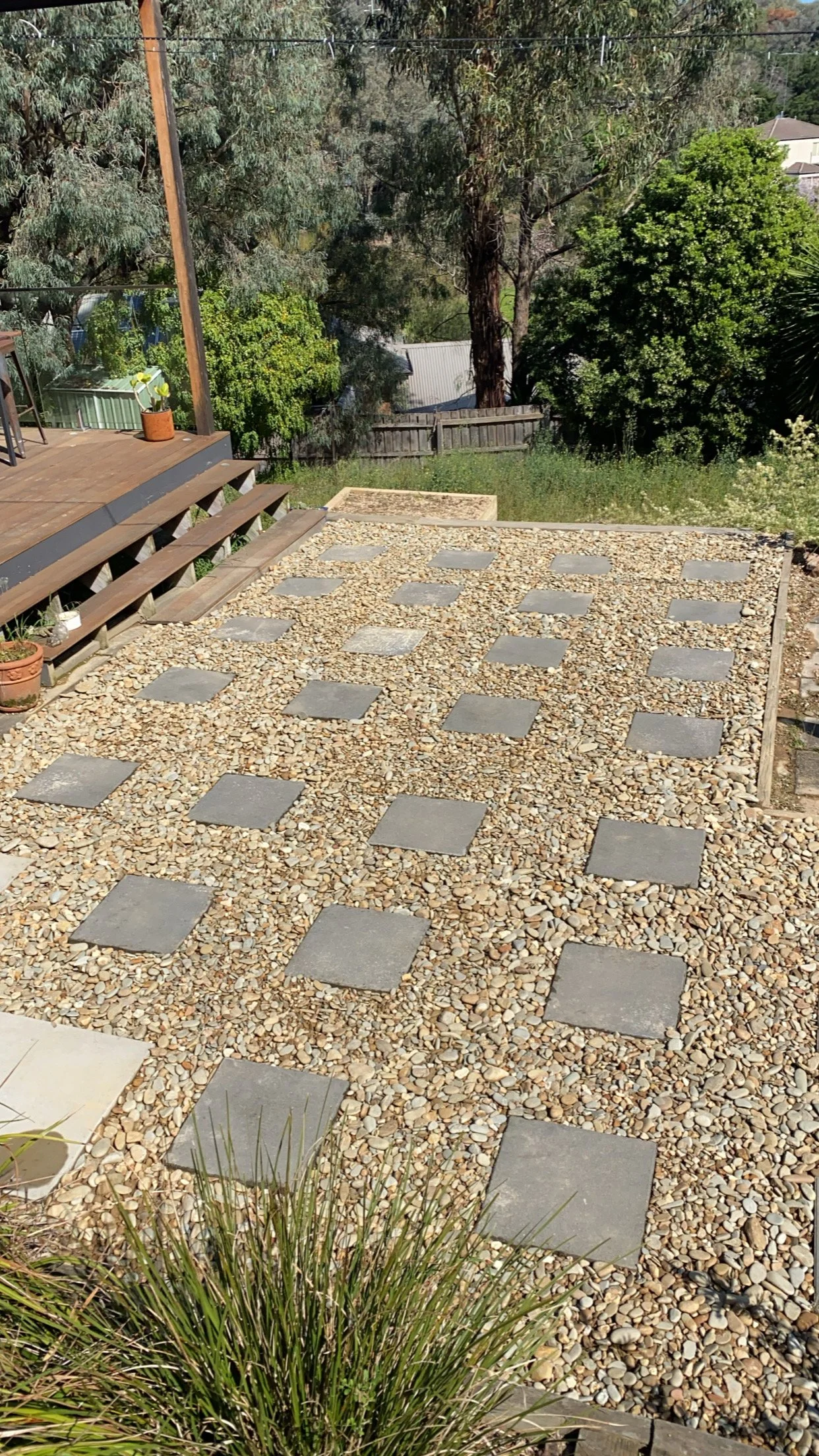 Backyard patio with steps
leading to gravel area with square pavers.