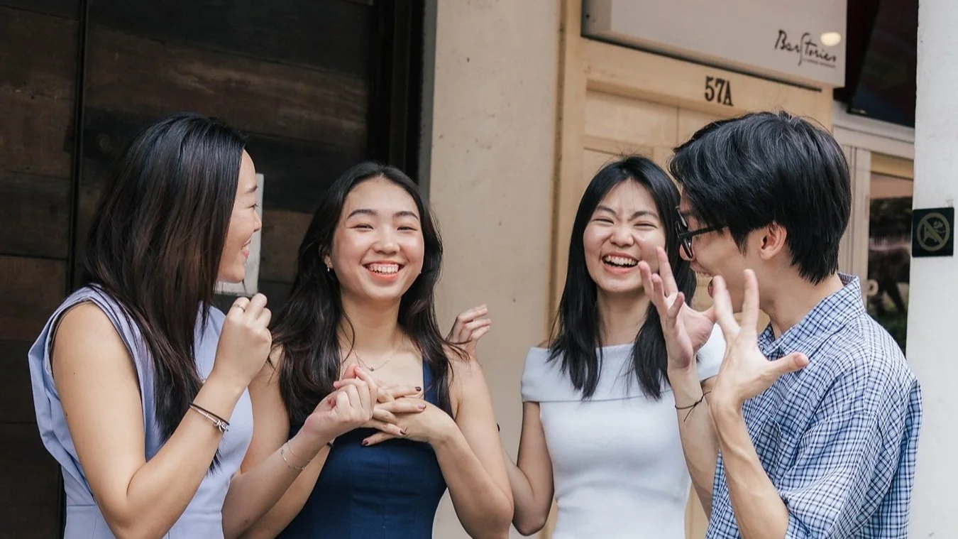 Group of four friends laughing and talking outdoors.