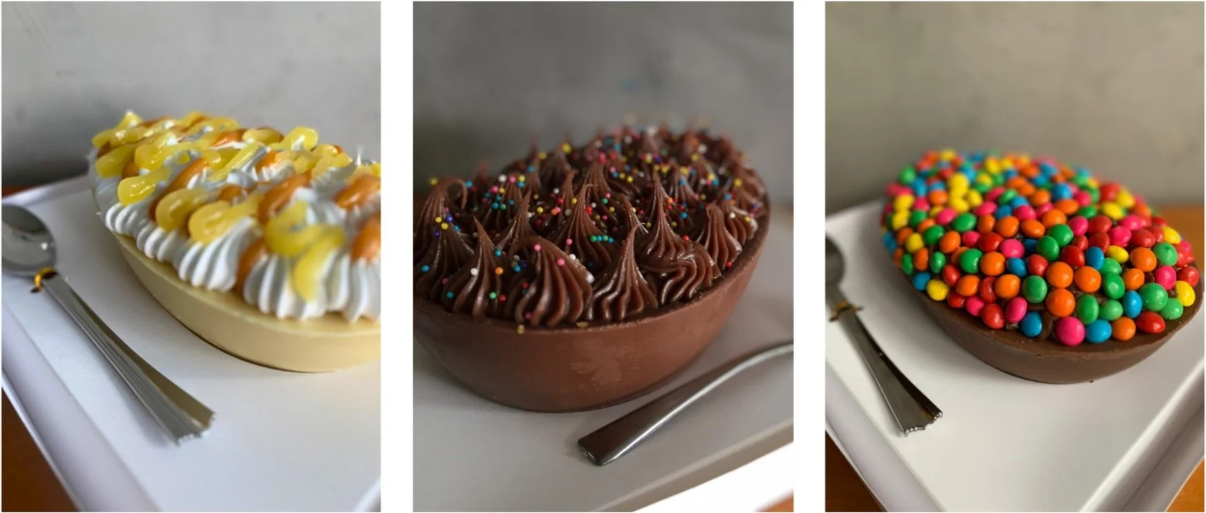 Three decorated chocolate Easter eggs with various toppings on white trays