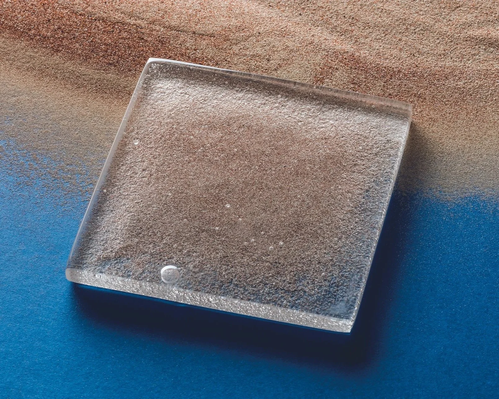 Square glass tile infused with desert sand as part of the Arenophile collection