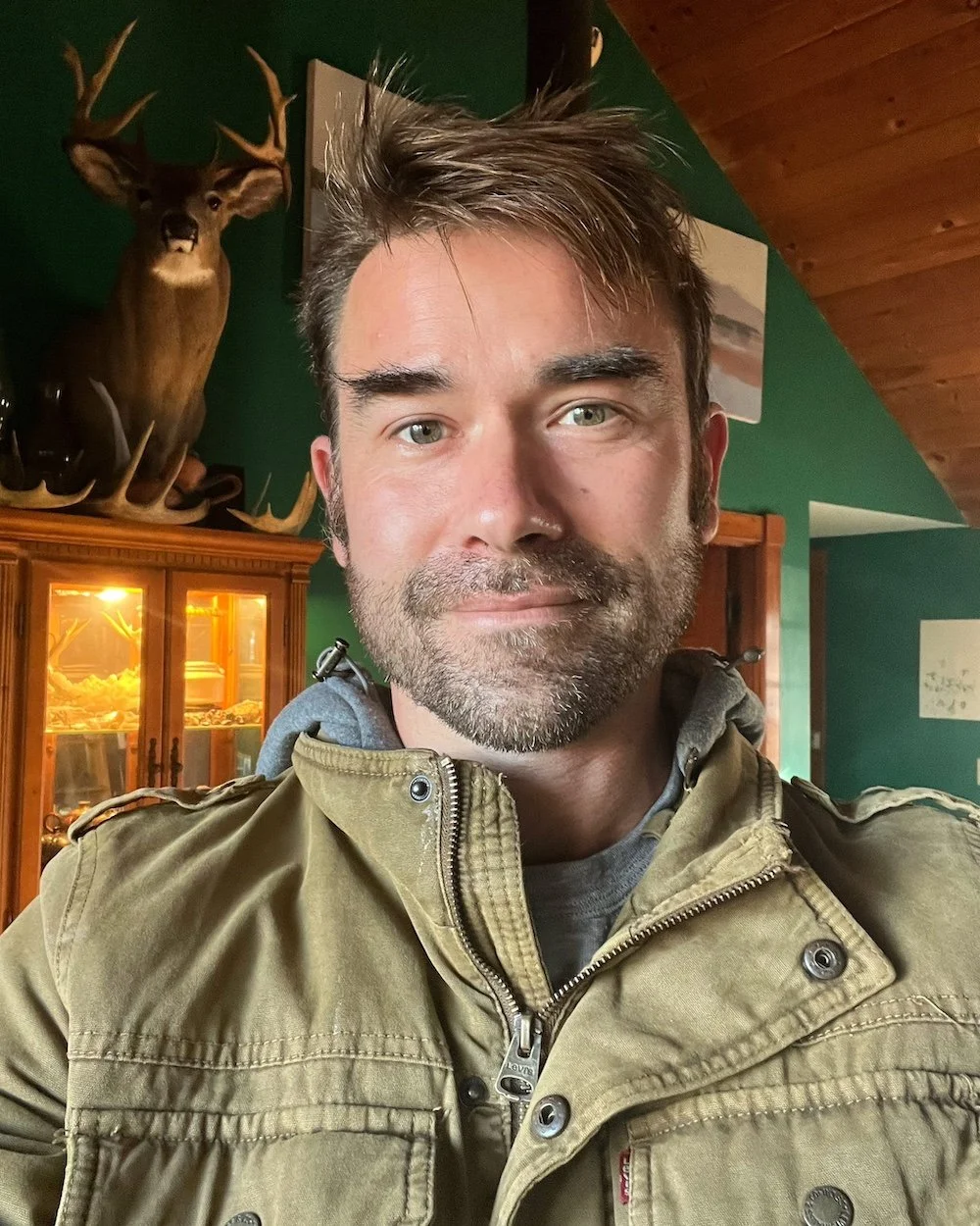 A handsome man with stubble wearing a brown jacket