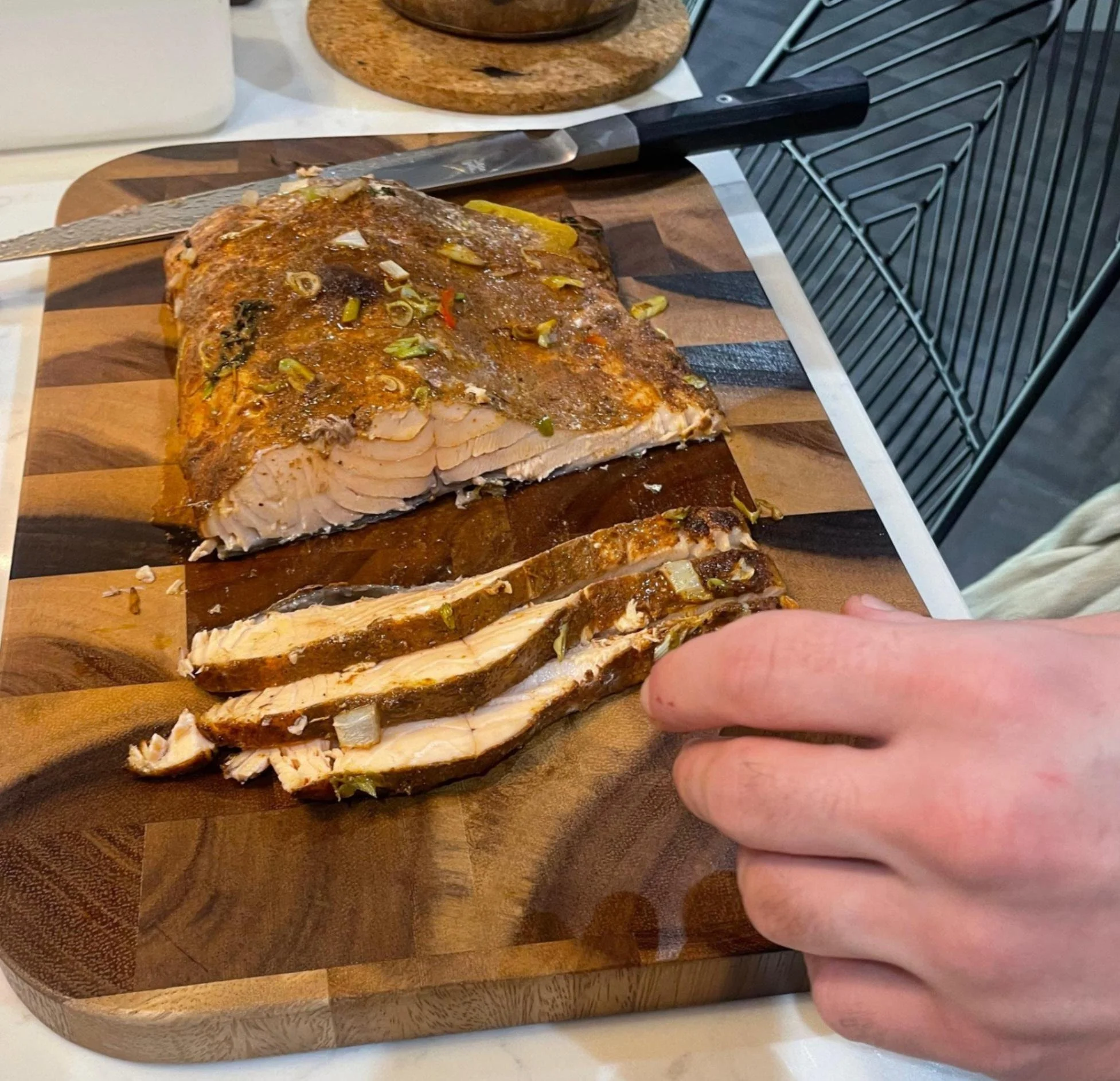 Spiced roasted salmon being sliced on a wooden board in the Greek Tings kitchen.