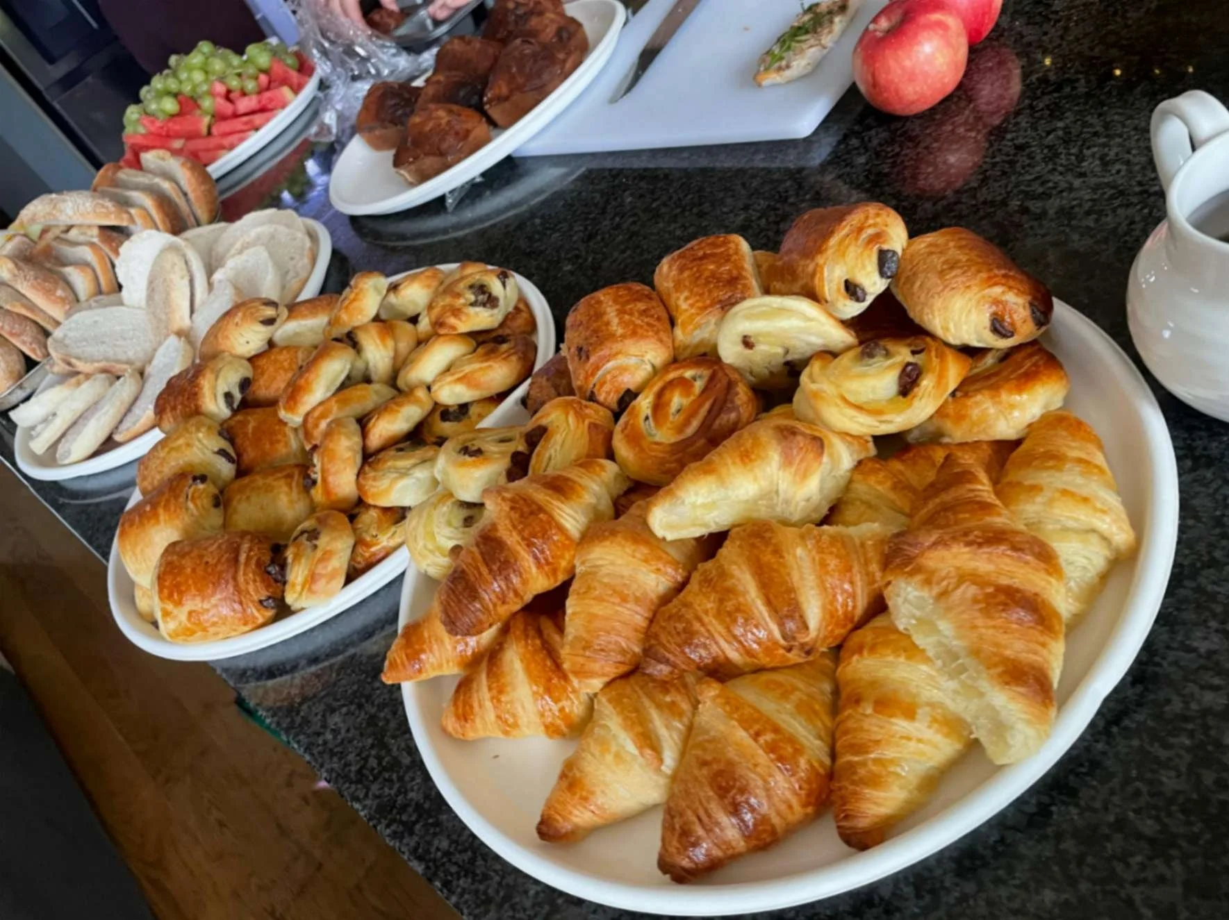 Breakfast spread with croissants, pastries, breads and fresh fruit.
